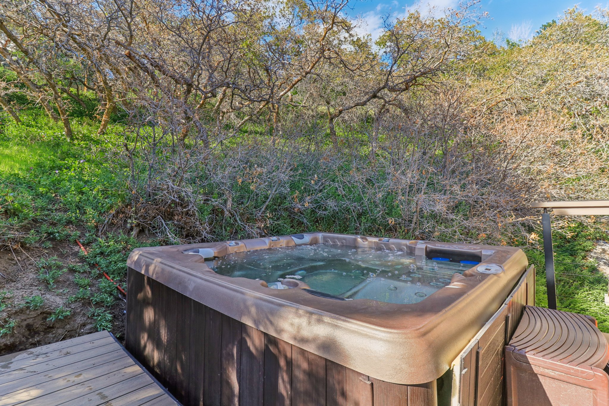 Outdoor hot tub with wood-finish siding and integrated steps, set on a wooden deck