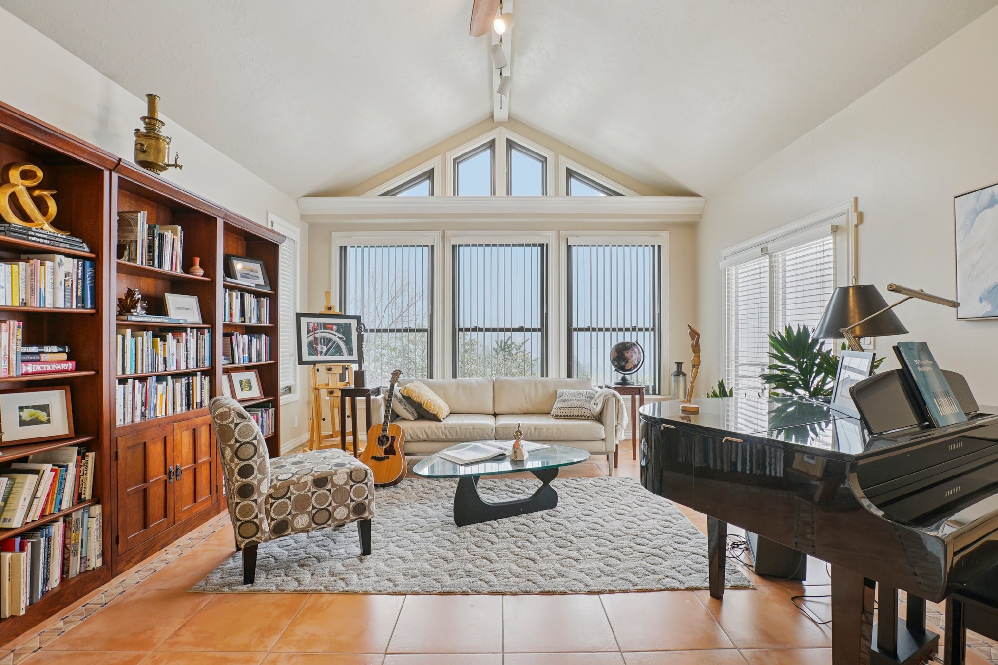 Spacious living area featuring a vaulted ceiling with clerestory windows, tile flooring, and a wall of built-in wood cabinetry