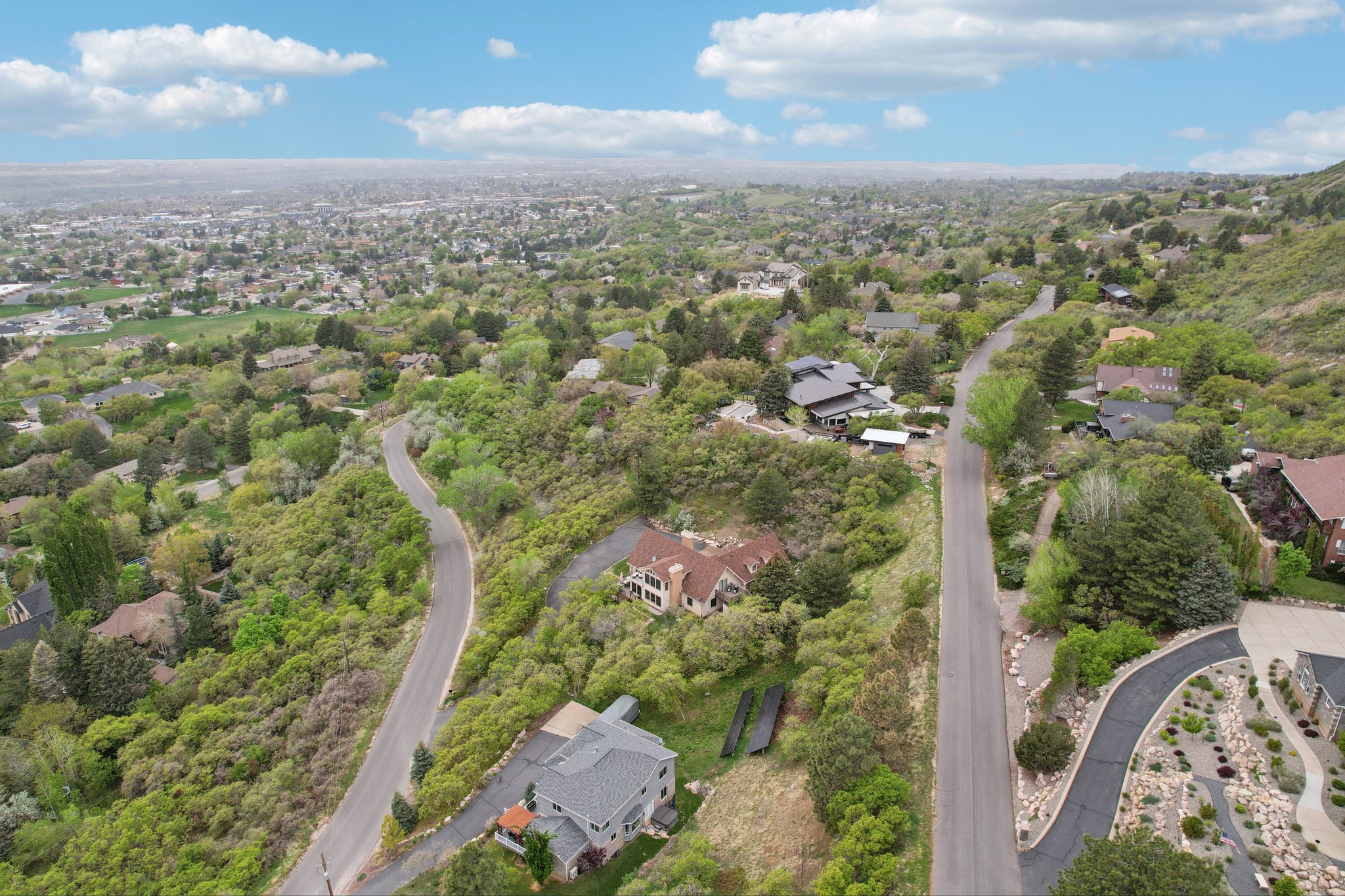 Aerial perspective showcasing a residential area nestled within a lush, tree-filled landscape