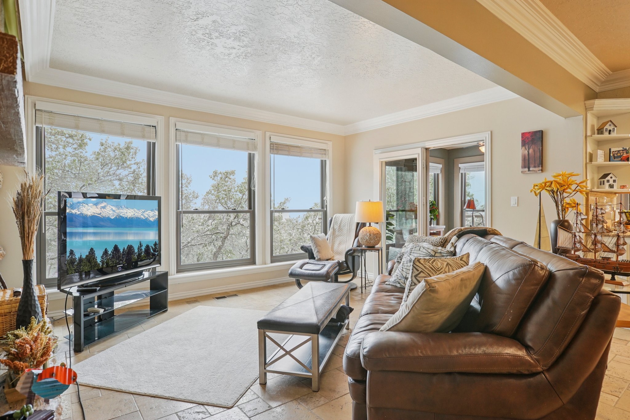 Living area featuring large windows, recessed ceiling, tile flooring, and integrated shelving