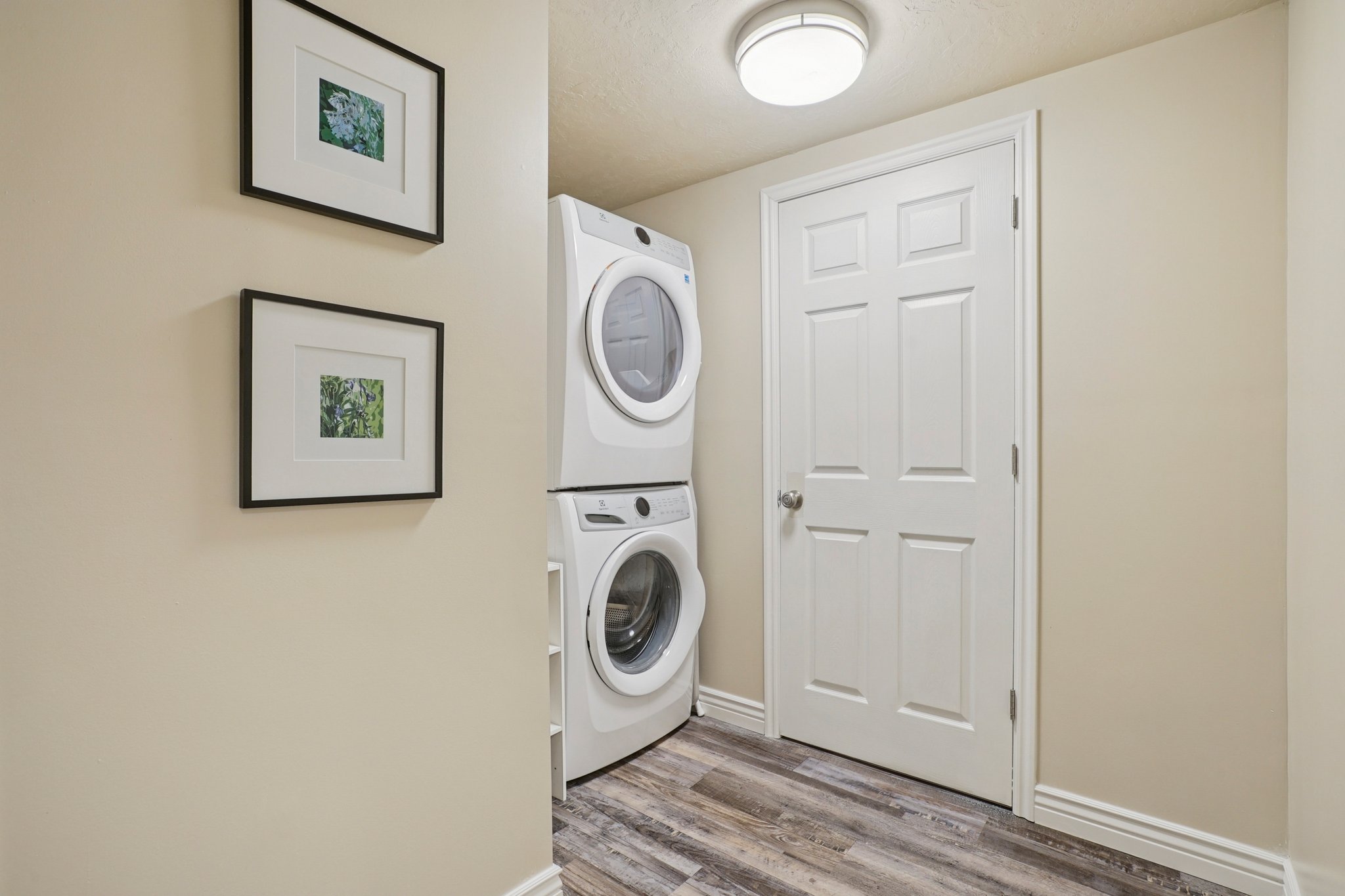 Dedicated laundry area featuring a stacked washer and dryer, wood-finish flooring, and a six-panel interior door