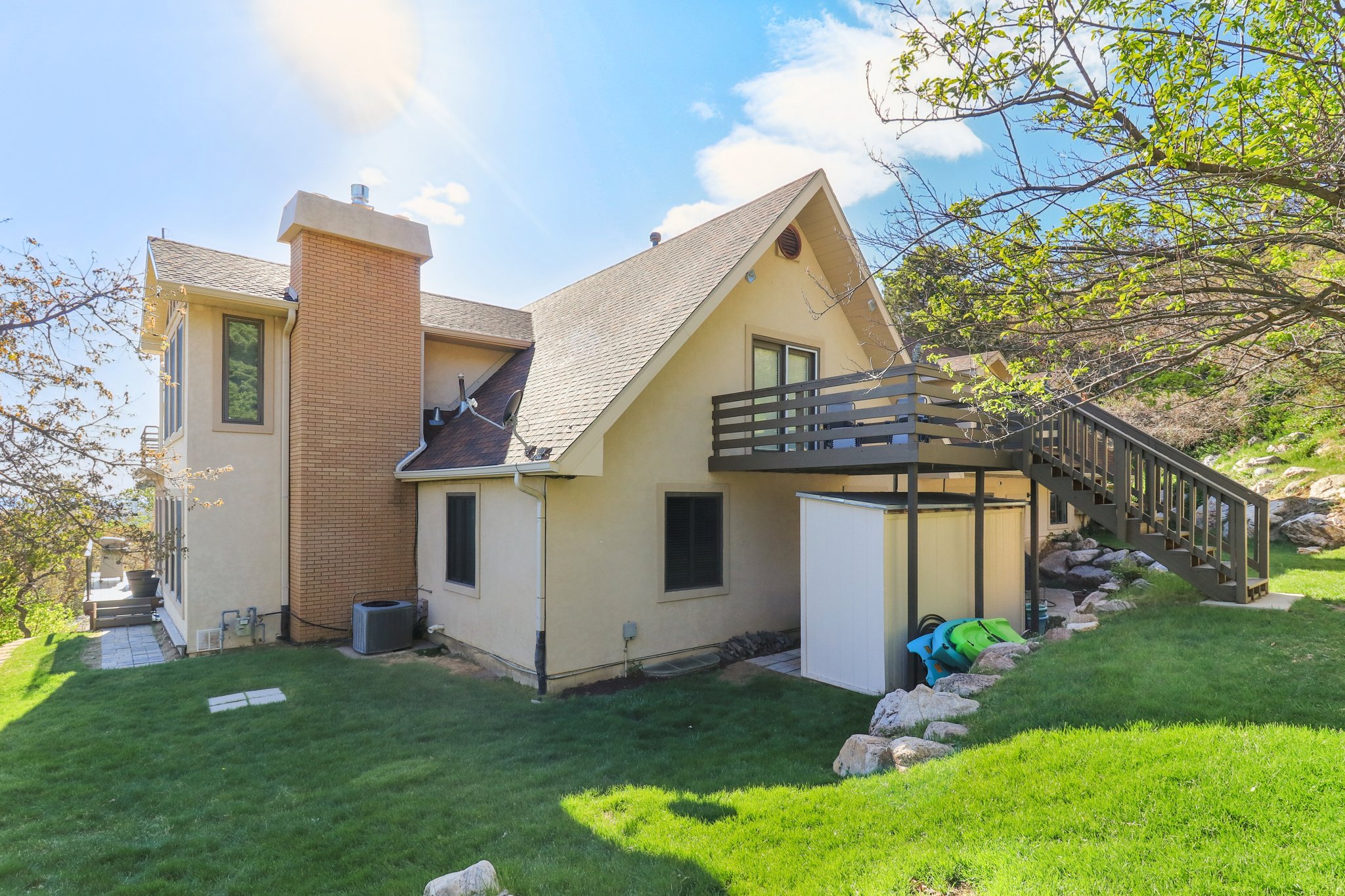 Rear exterior featuring a multi-level deck, a brick chimney, and a gently sloped lawn