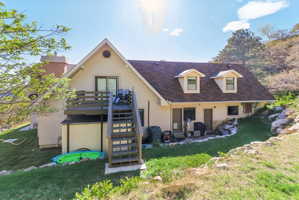 Two-story rear exterior featuring a deck with stairs, two dormer windows, and a lower-level patio
