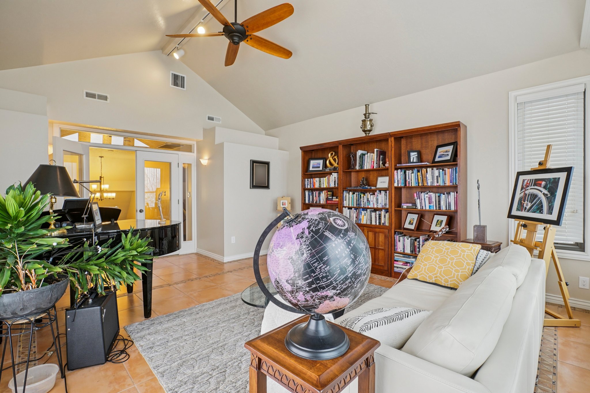 Spacious living area featuring vaulted ceilings with a ceiling fan, tile flooring, and integrated track lighting