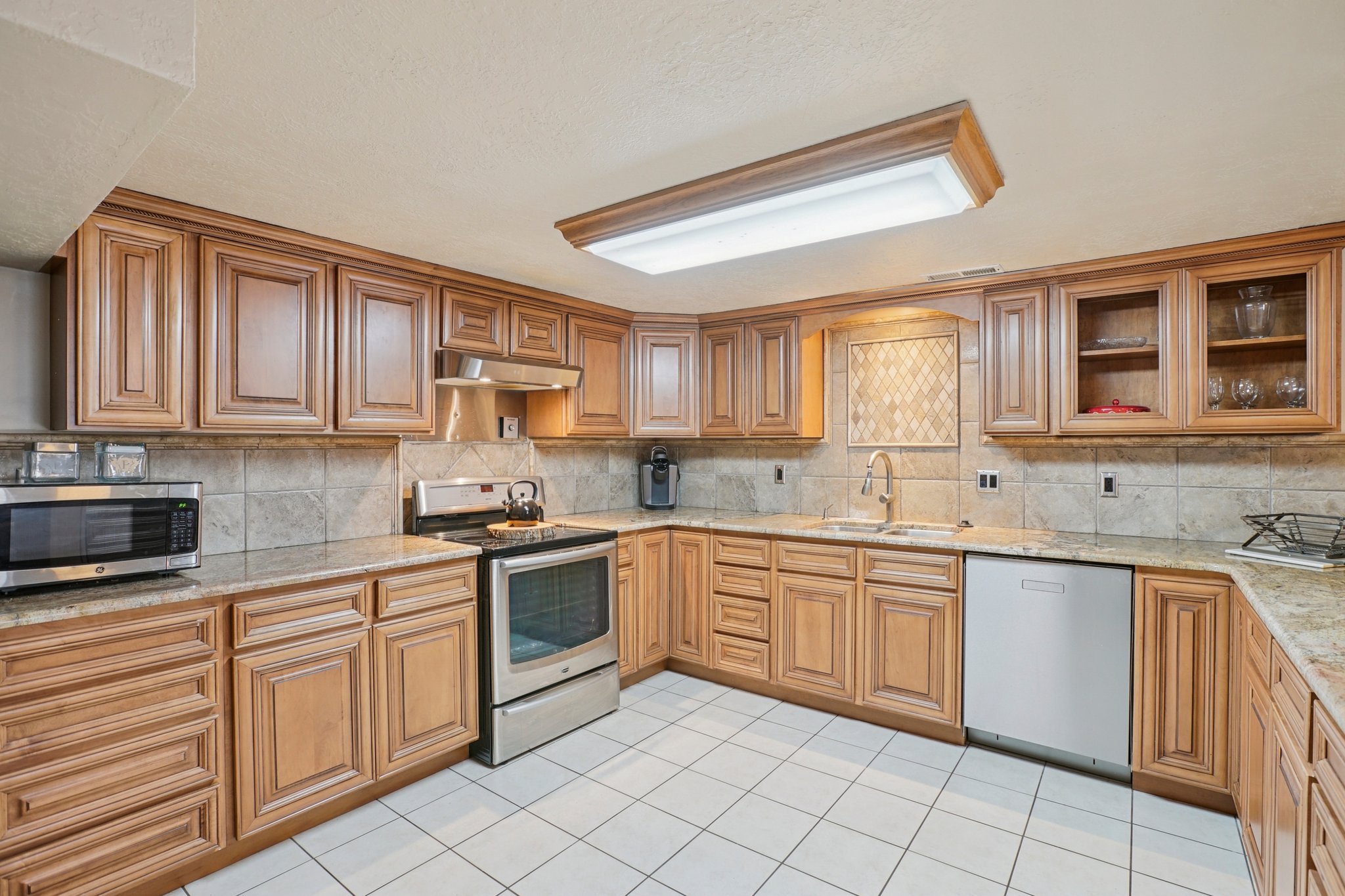 Kitchen with extensive wood-finish cabinetry, light-toned countertops, and a tile backsplash