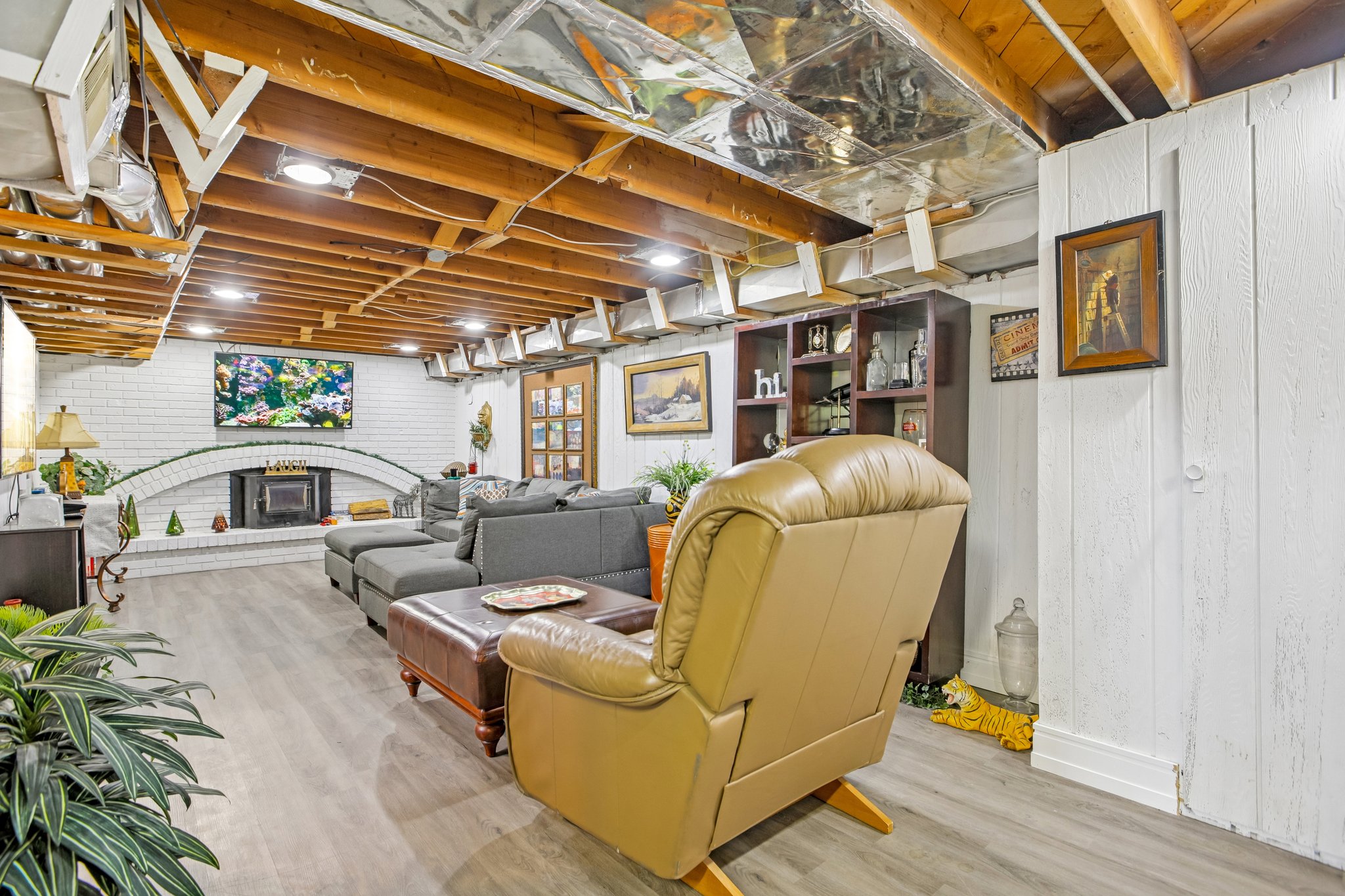 Spacious recreational room featuring wood-finish flooring, an exposed wood beam ceiling, and recessed lighting