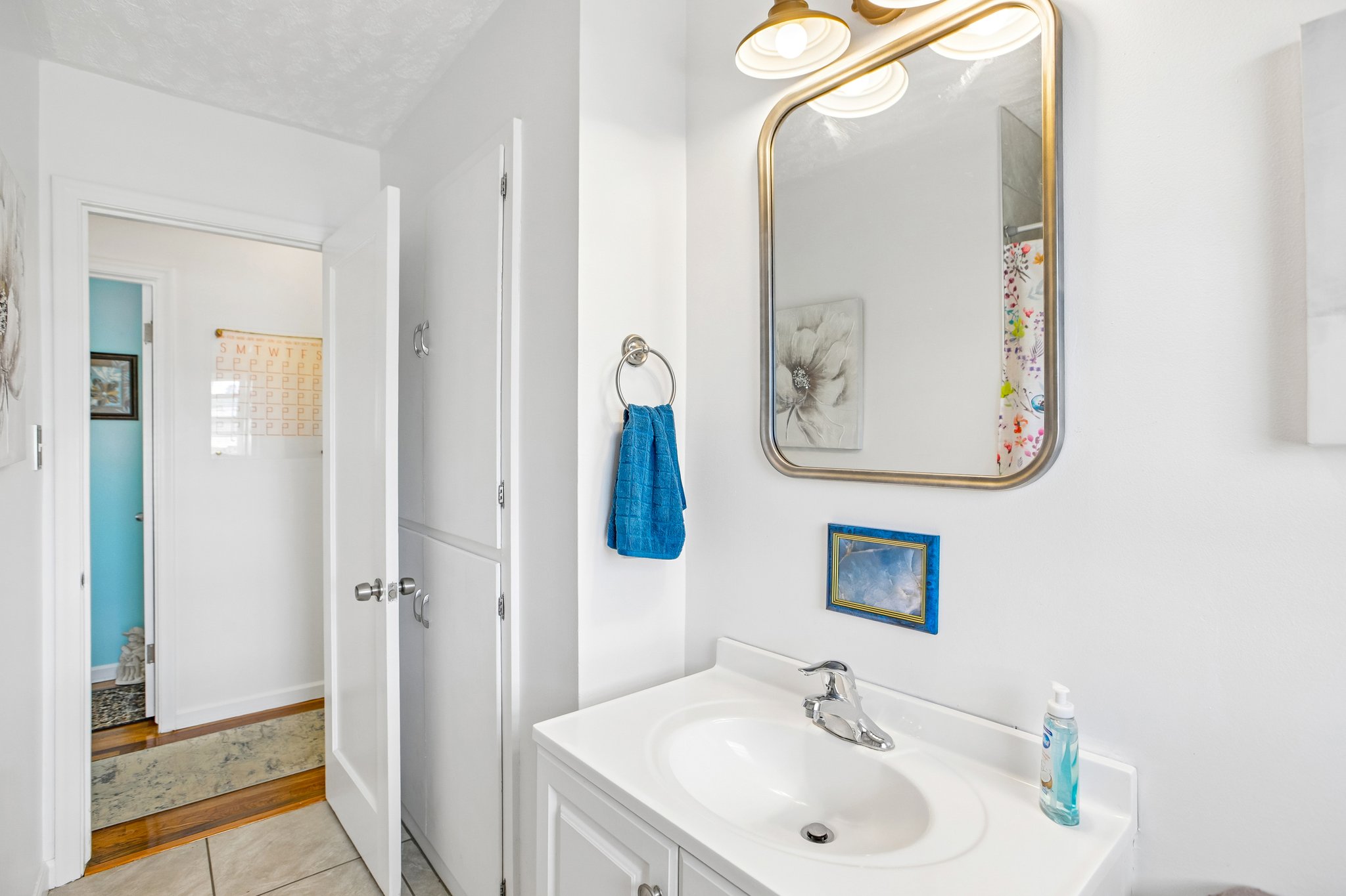 White vanity with integrated sink, chrome faucet, and a gold-framed mirror
