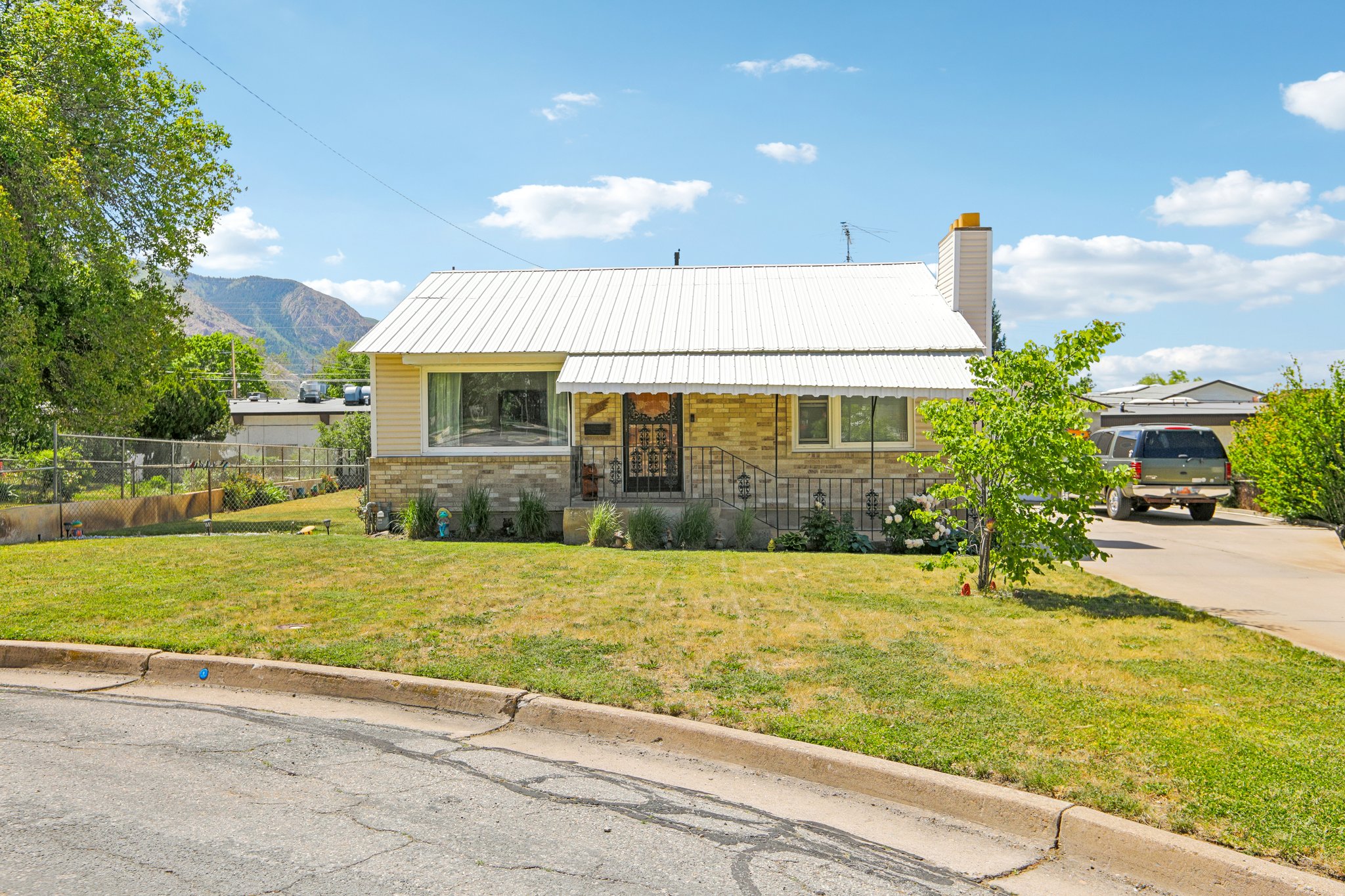 Single-story residence featuring a metal roof, yellow siding, and a stone facade