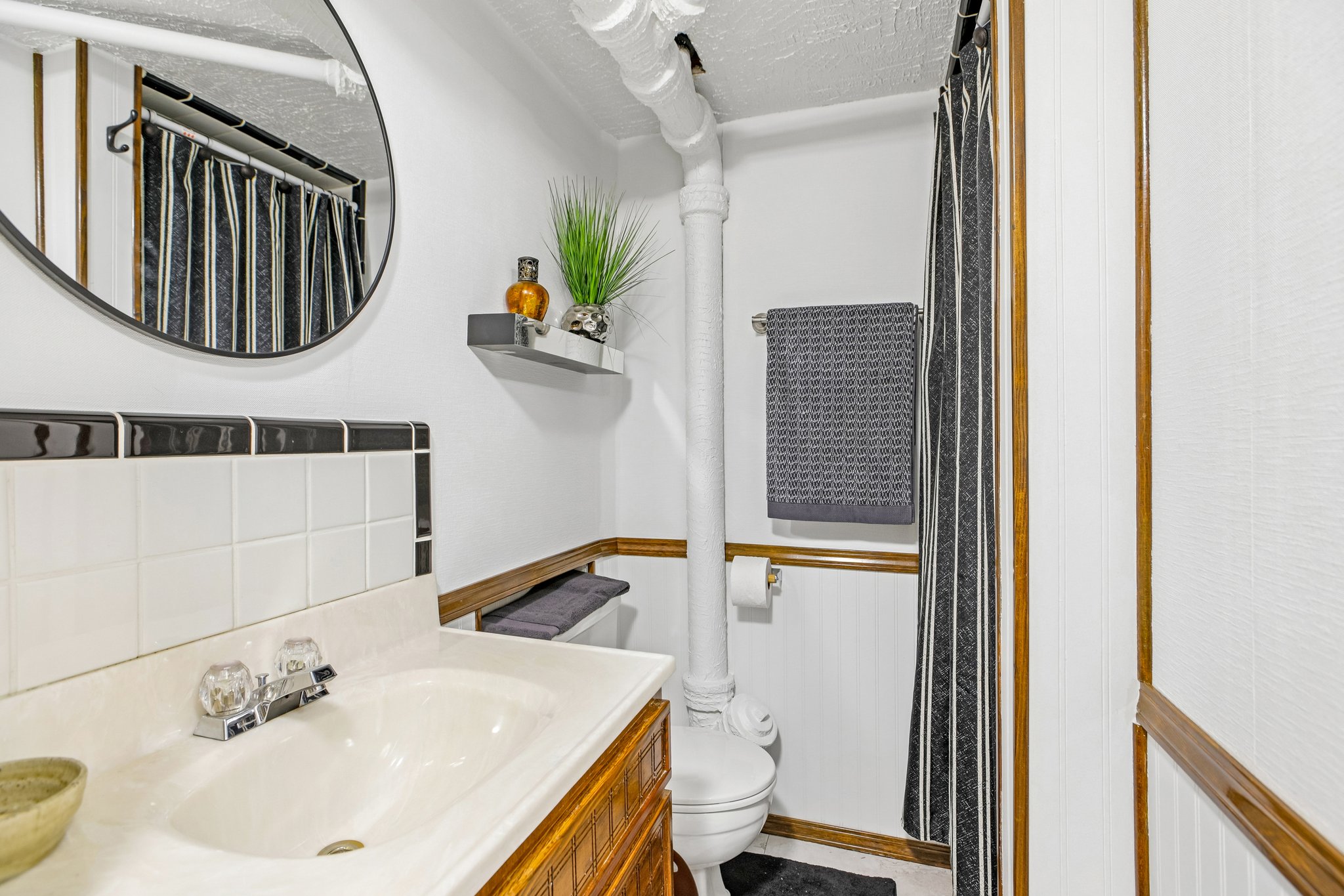 Bathroom vanity with integrated sink, clear knob faucets, and a tiled backsplash featuring a black decorative border