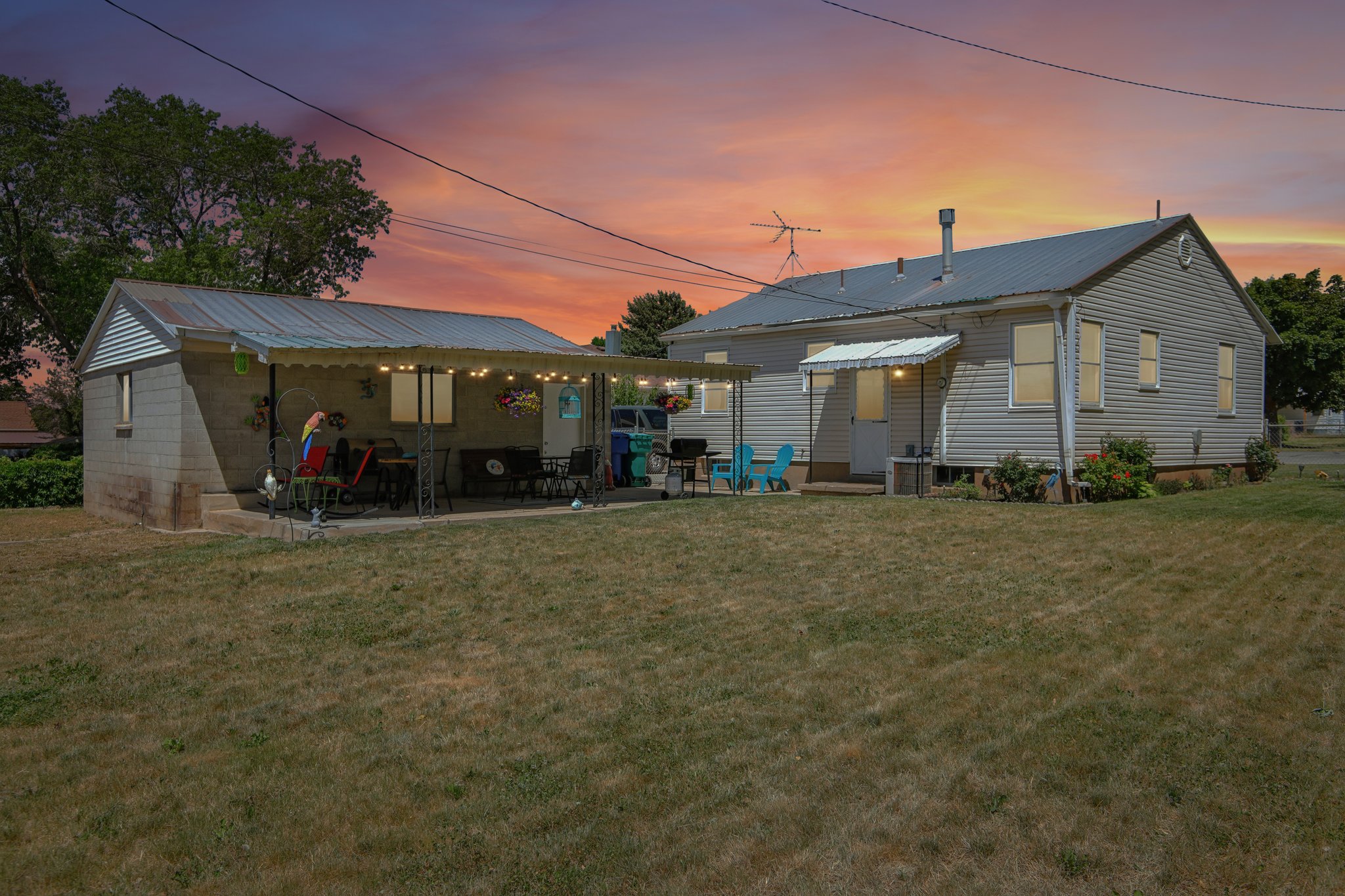 Expansive backyard featuring a detached garage with a covered patio, a main residence with siding exterior, and a metal roof