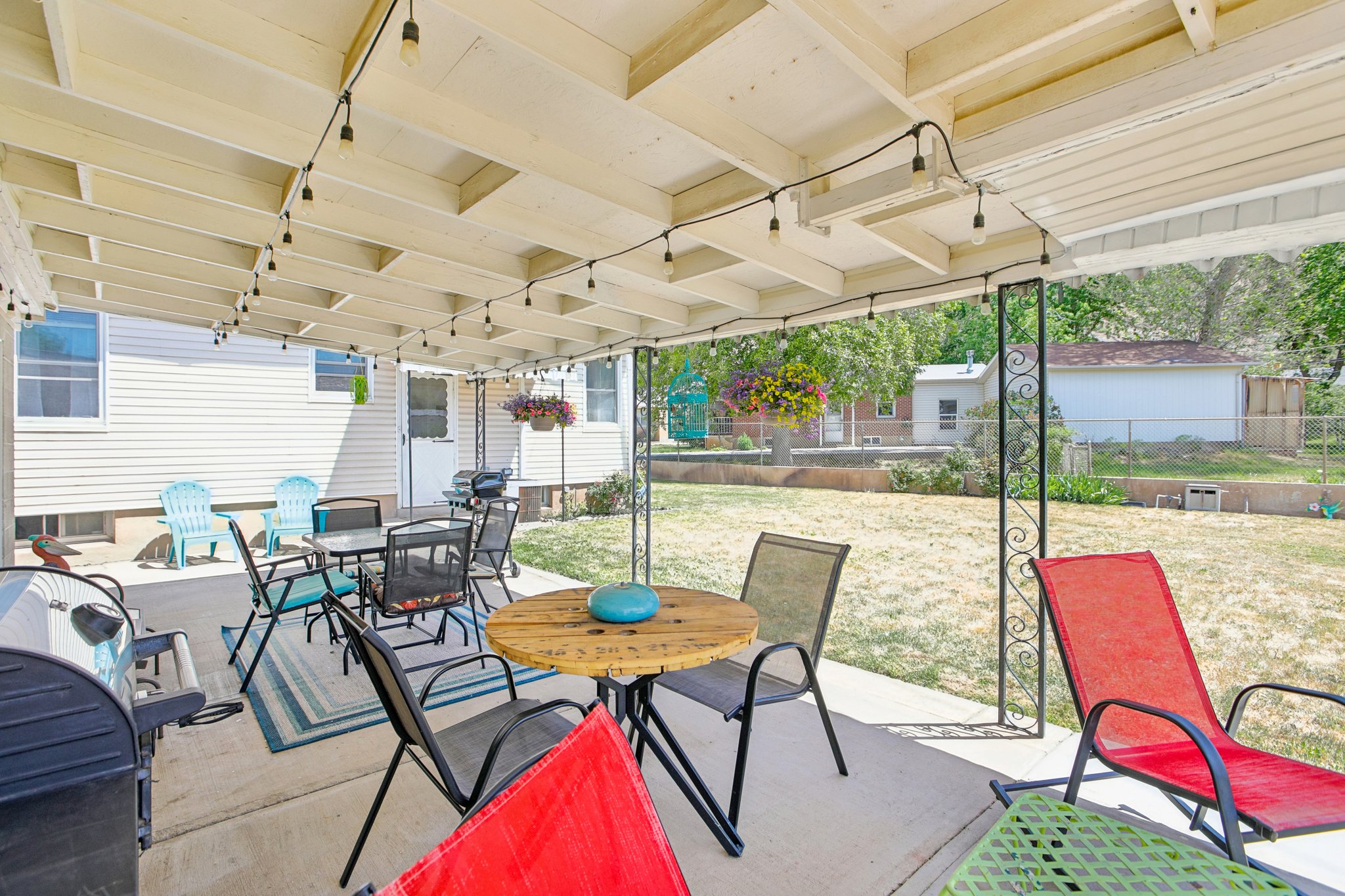Covered patio with string lights, concrete flooring, and wrought iron support posts