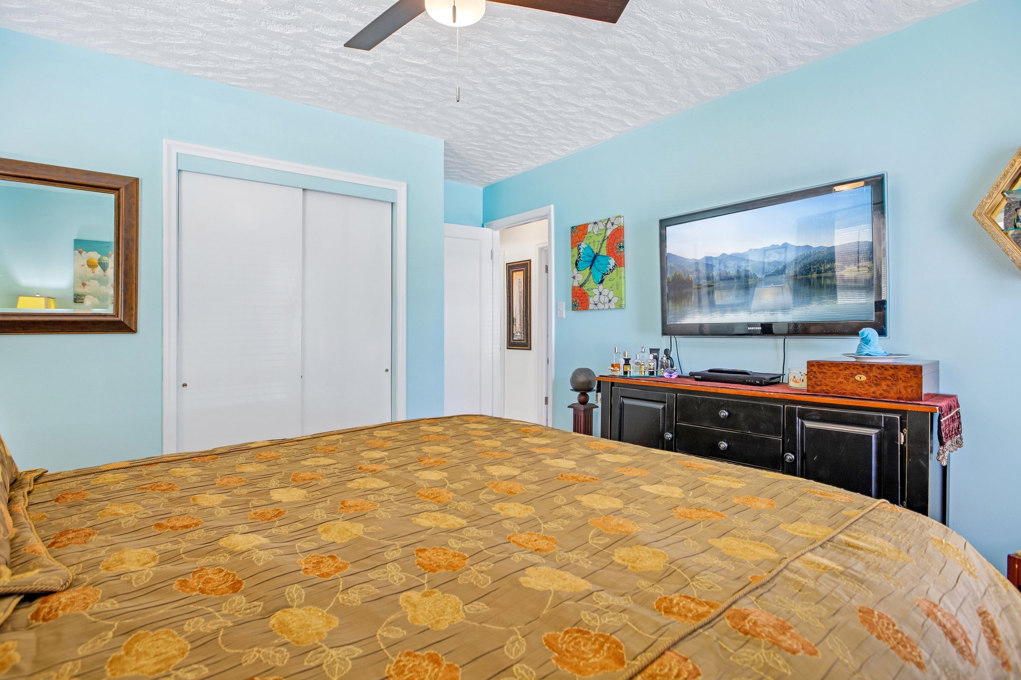 Bedroom featuring a ceiling fan with light fixture, sliding closet doors, and light blue wall paint