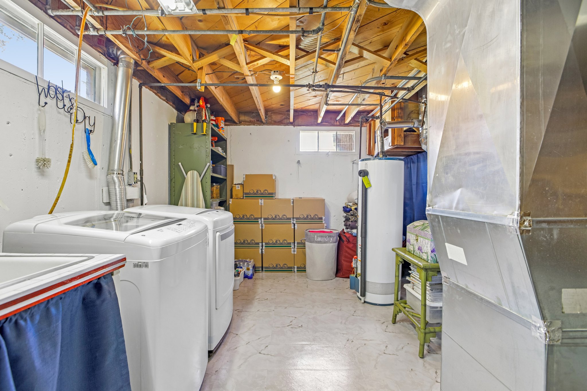 Utility room featuring exposed ceiling joists, concrete flooring, and a window for natural light