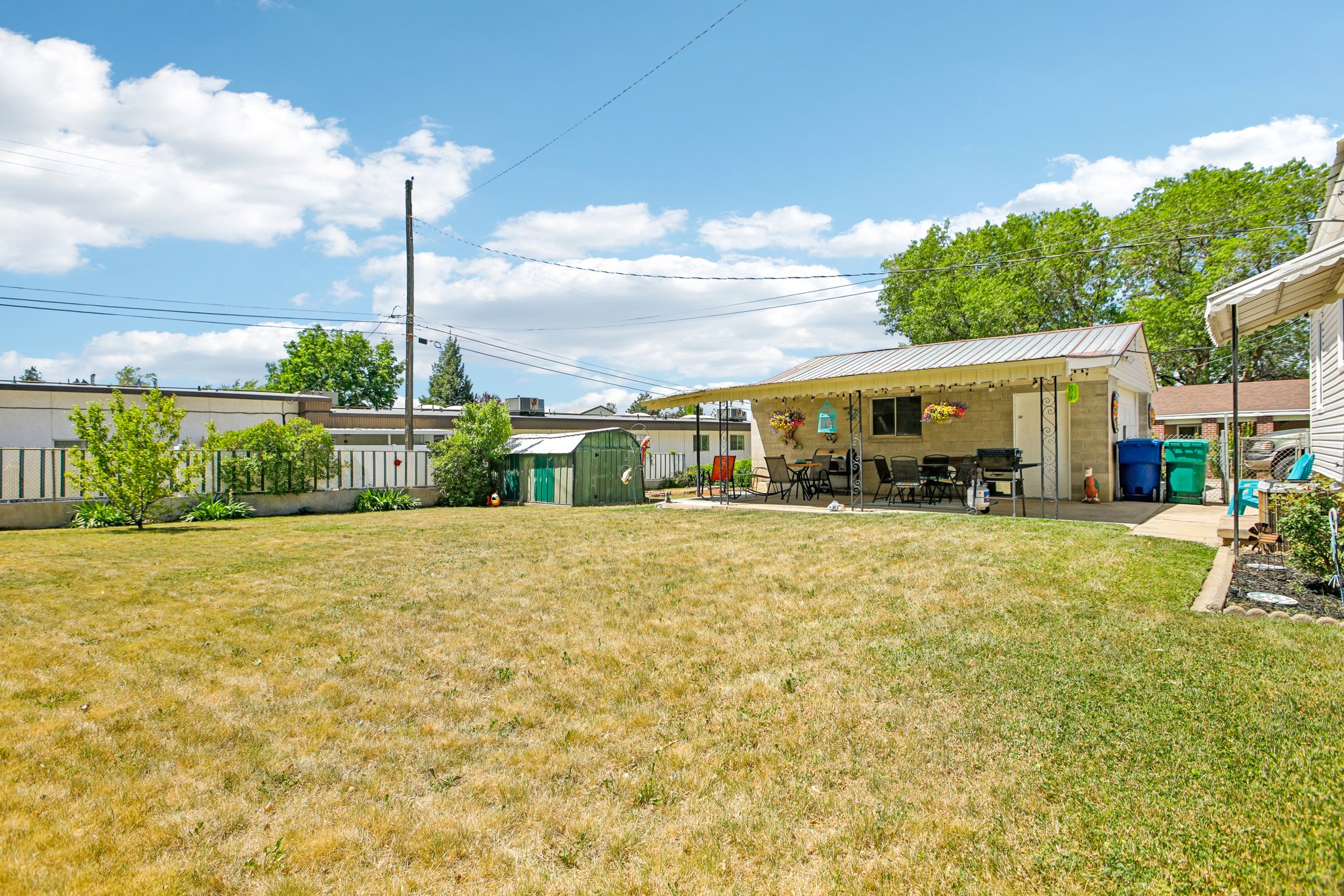 Expansive backyard featuring a large grass area and a concrete patio with a covered awning