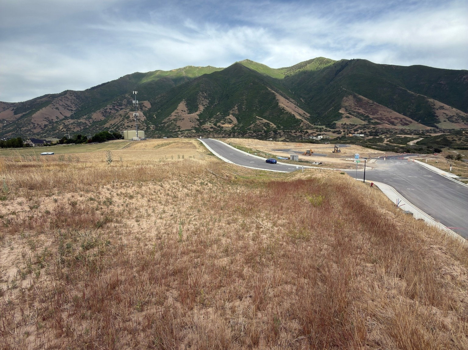 Expansive undeveloped land featuring a paved road and mountainous backdrop