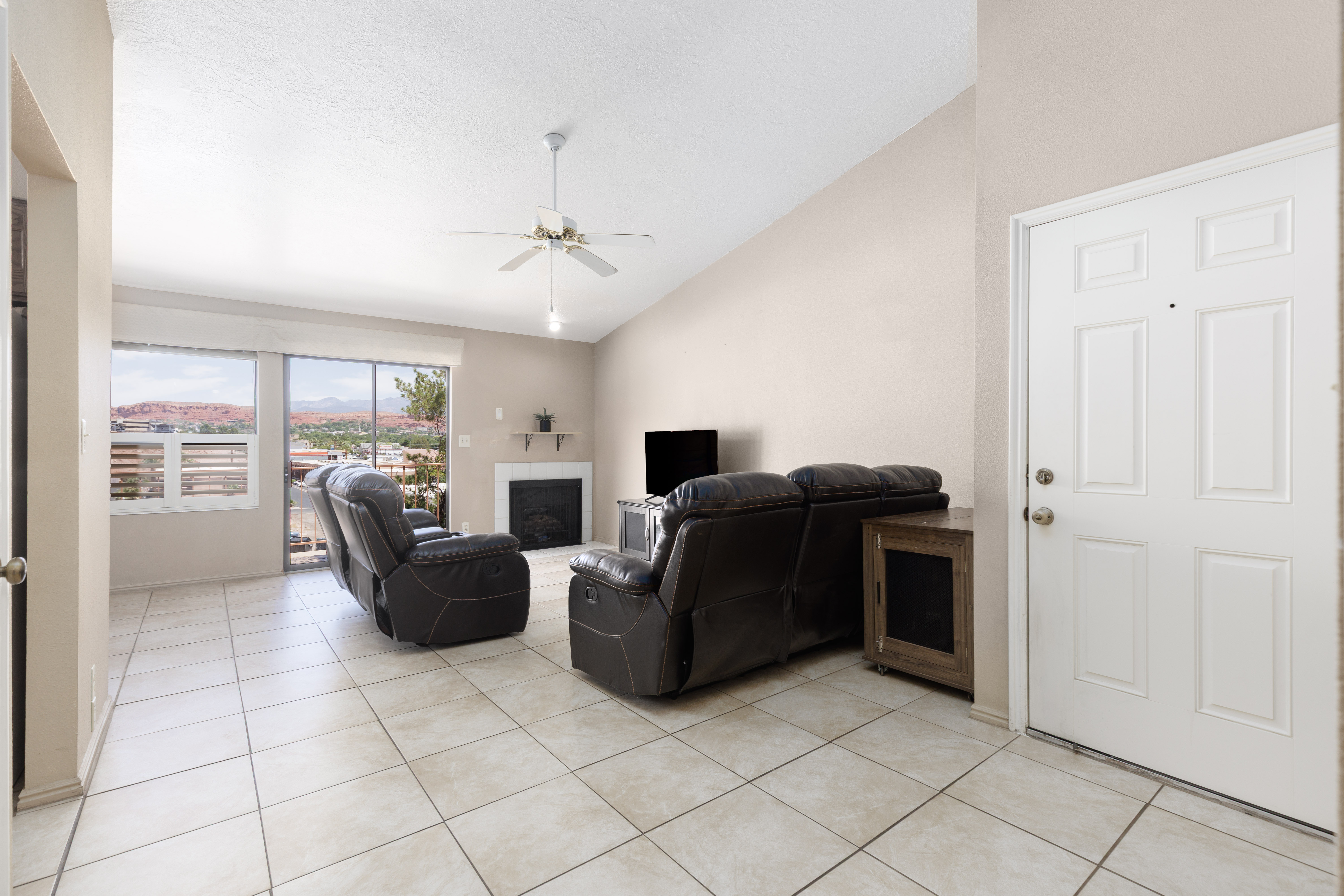 Living area featuring light-toned tile flooring and a vaulted ceiling with a ceiling fan