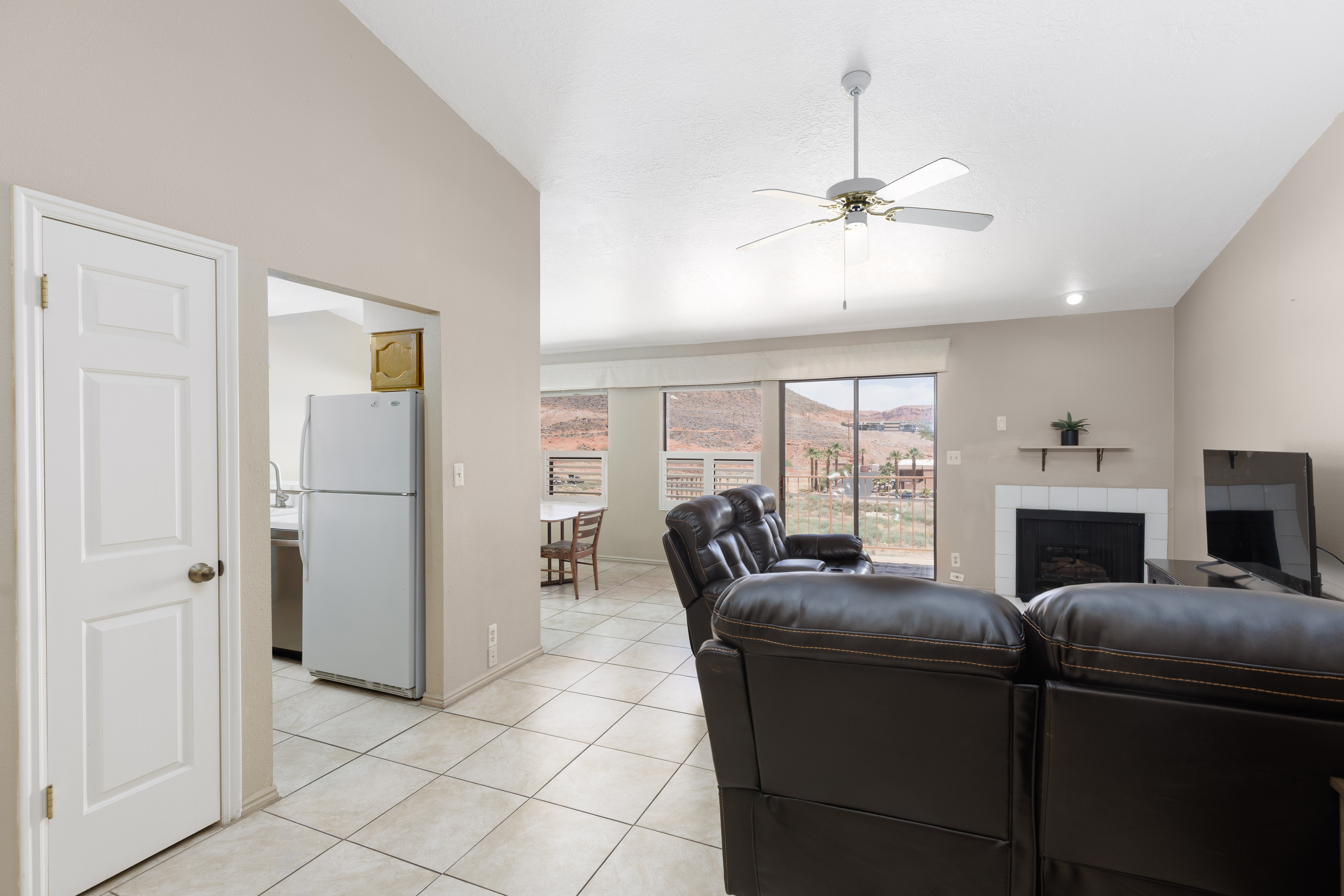 Living area featuring tile flooring, a vaulted ceiling, and a ceiling fan