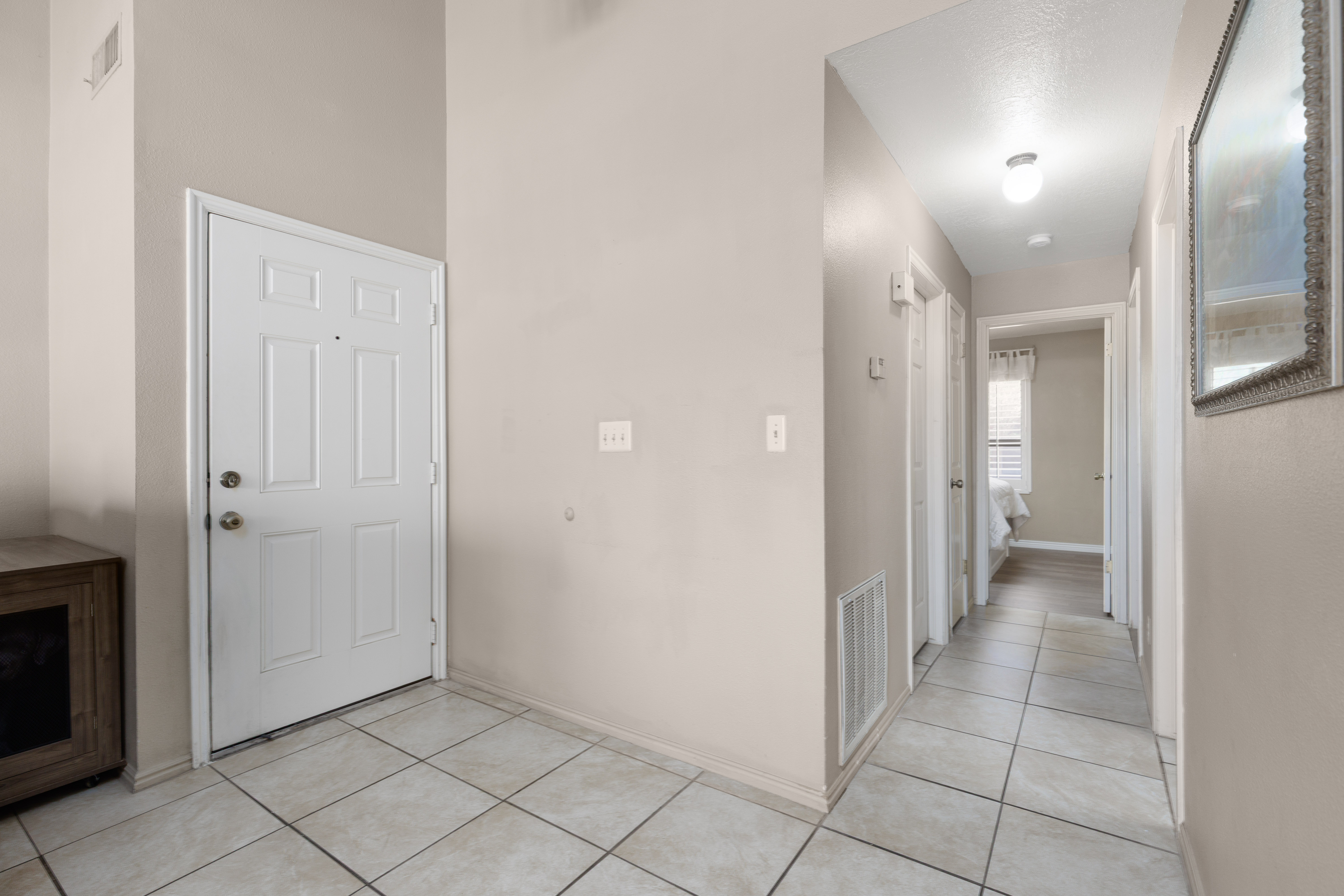 Entry foyer featuring light-colored tile flooring, a paneled entry door, and vaulted ceilings