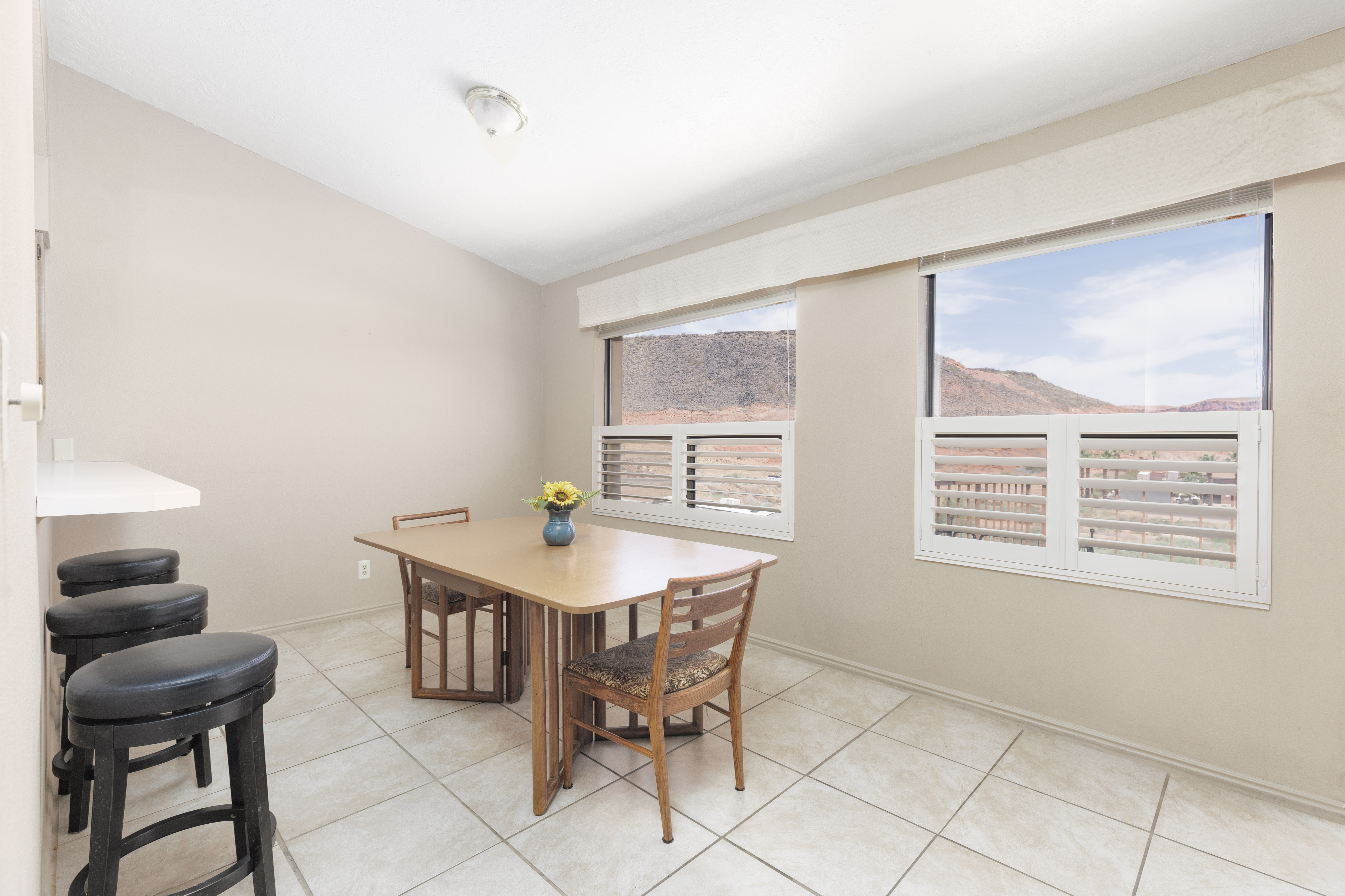 Dining area featuring tile flooring, neutral wall tones, and two windows with white plantation shutters
