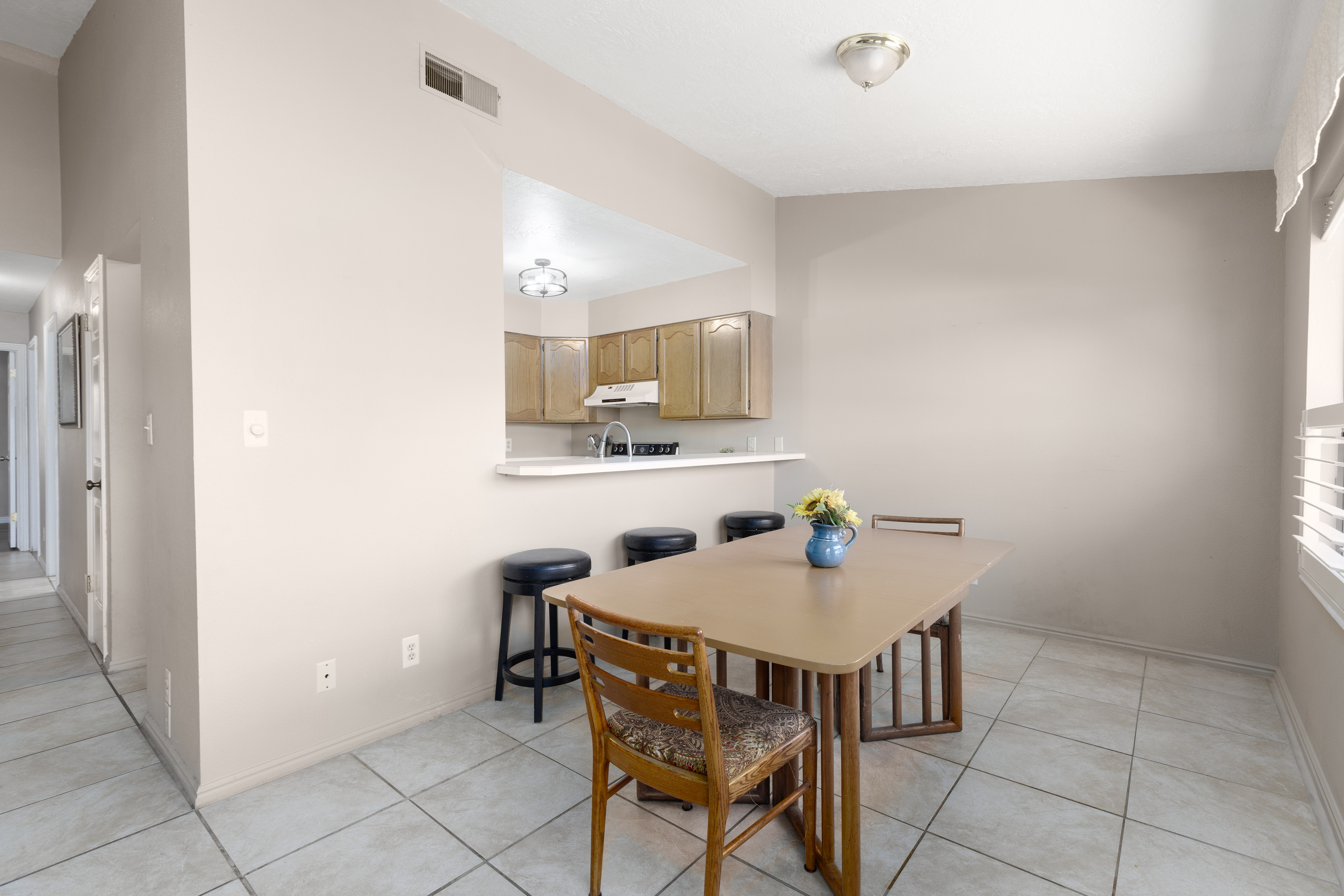 Dining area with tile flooring and a pass-through window to the kitchen with bar for extra seating