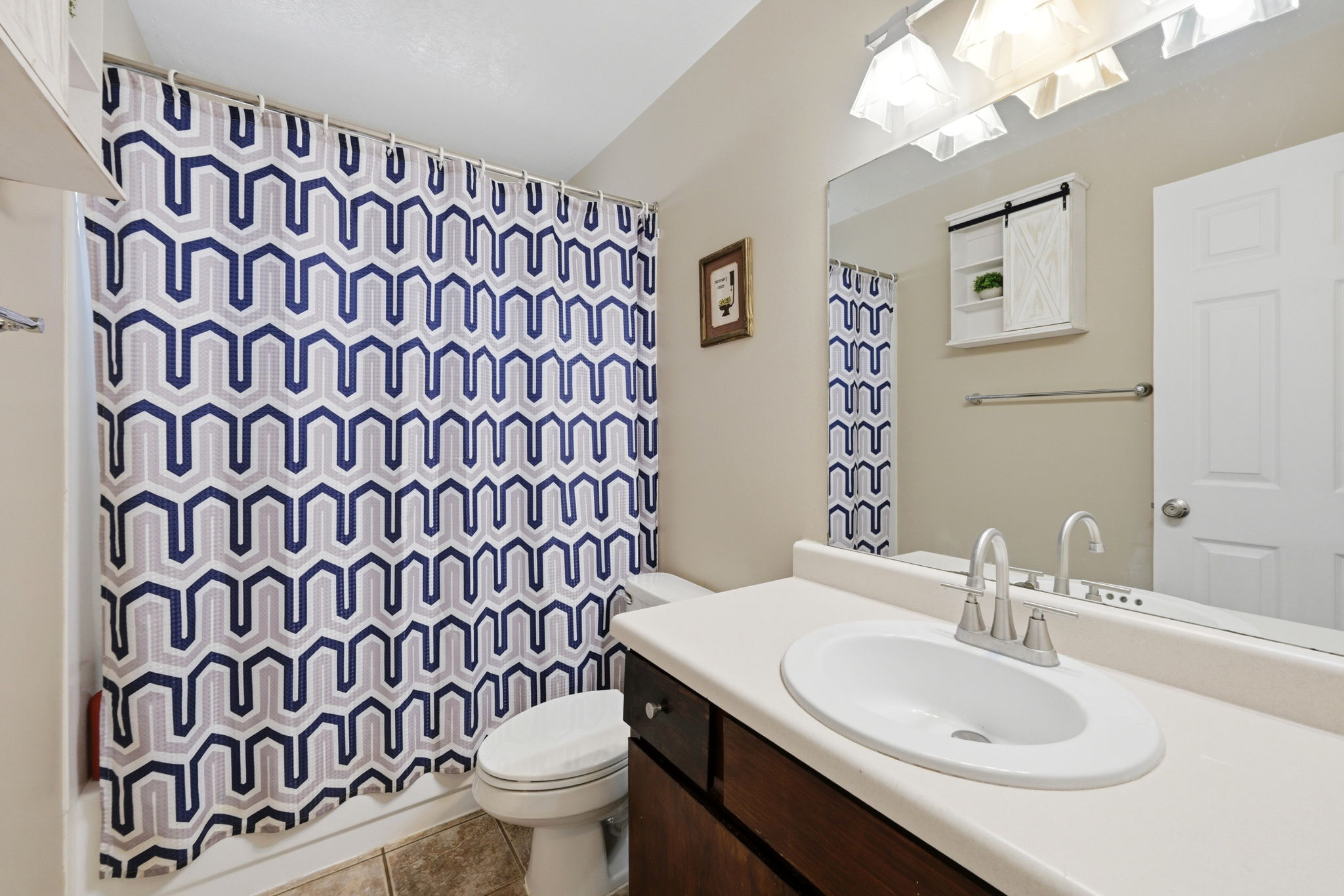 Bathroom vanity with a single basin sink, brushed nickel faucet, and a large wall-mounted mirror