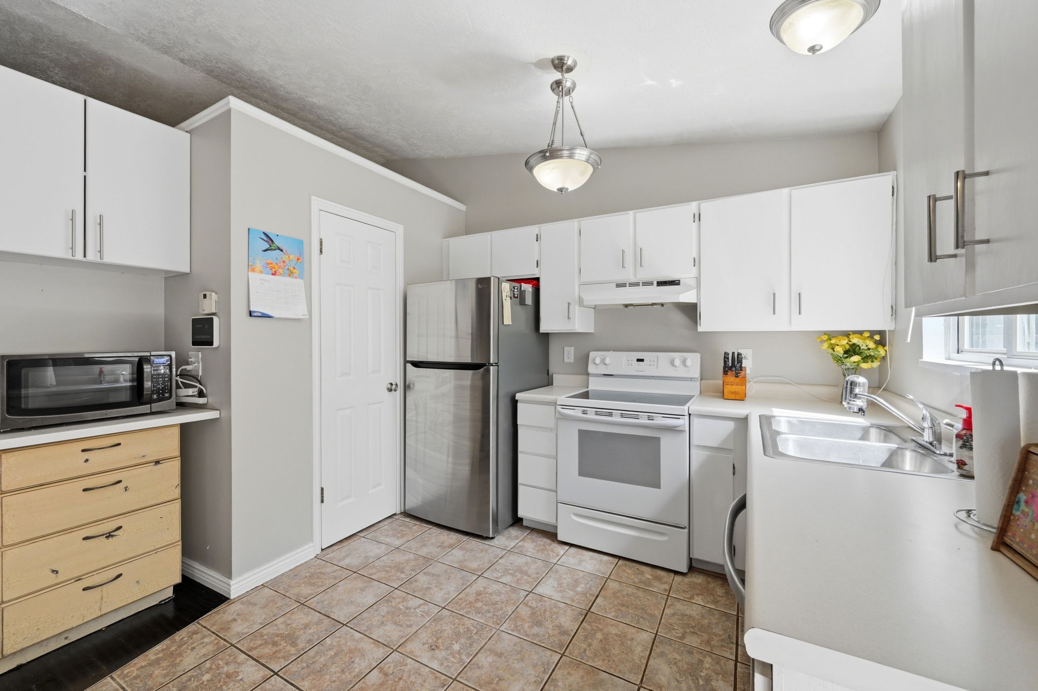 Kitchen featuring white cabinetry, stainless steel refrigerator, white electric range, and tile flooring