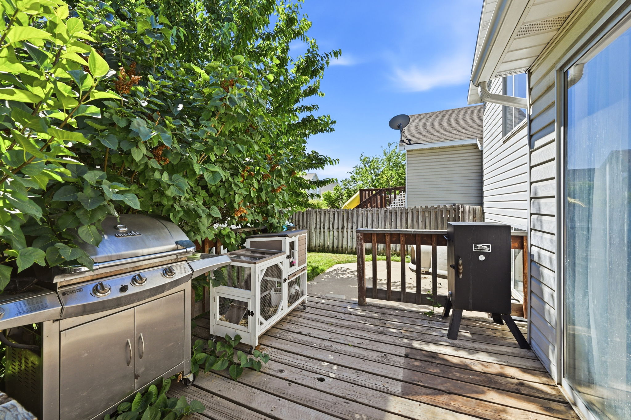 Expansive wood deck with an attached railing, siding exterior, and a sliding glass door