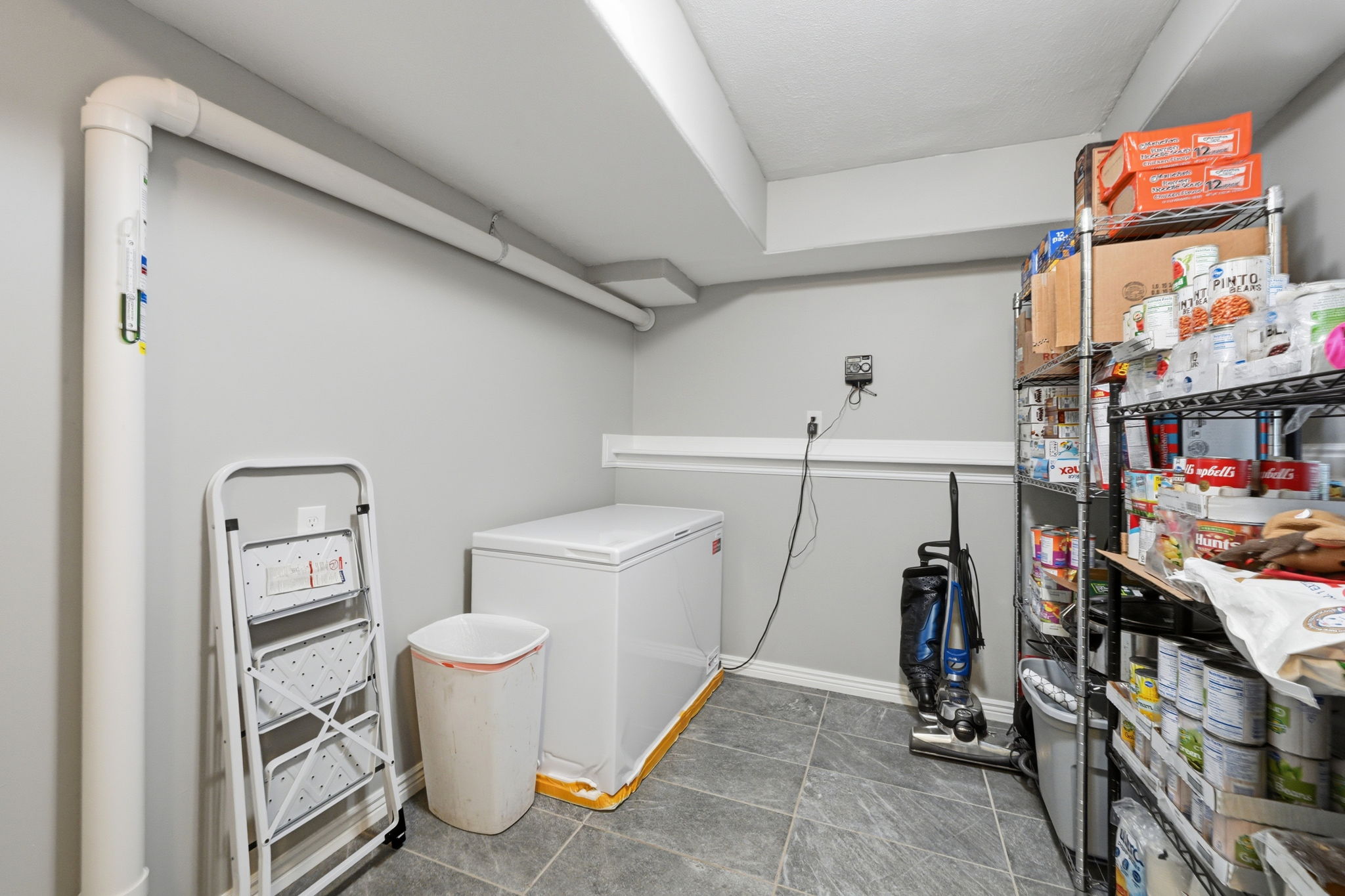 Utility room with gray painted walls, gray tile flooring, and exposed white ceiling beams