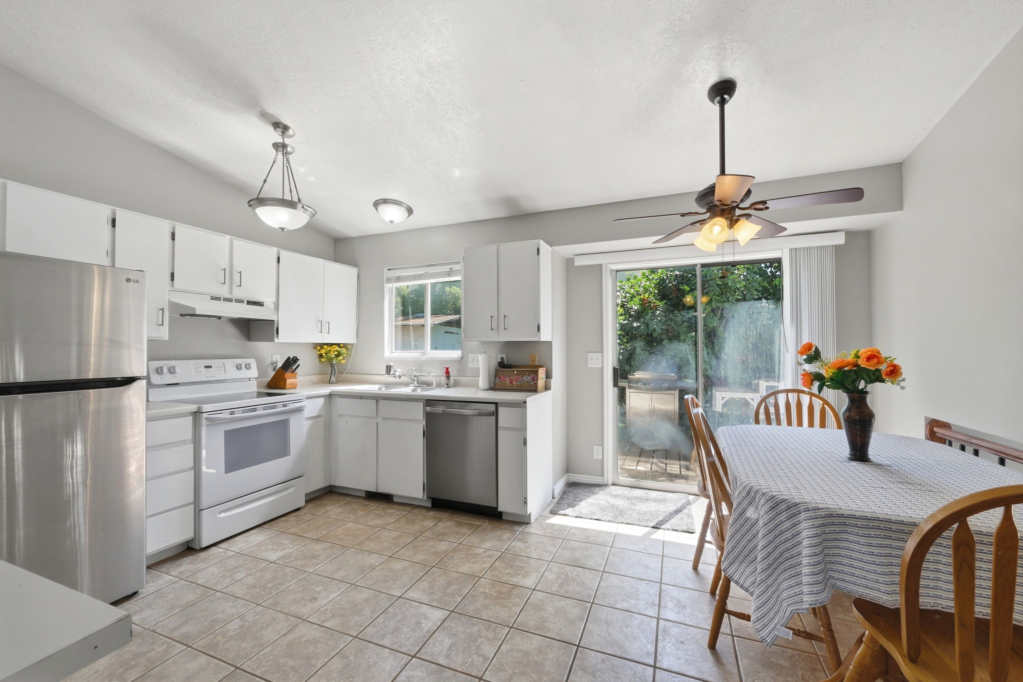 Kitchen featuring white cabinetry, tile flooring, stainless steel refrigerator, white range, and a sliding glass door