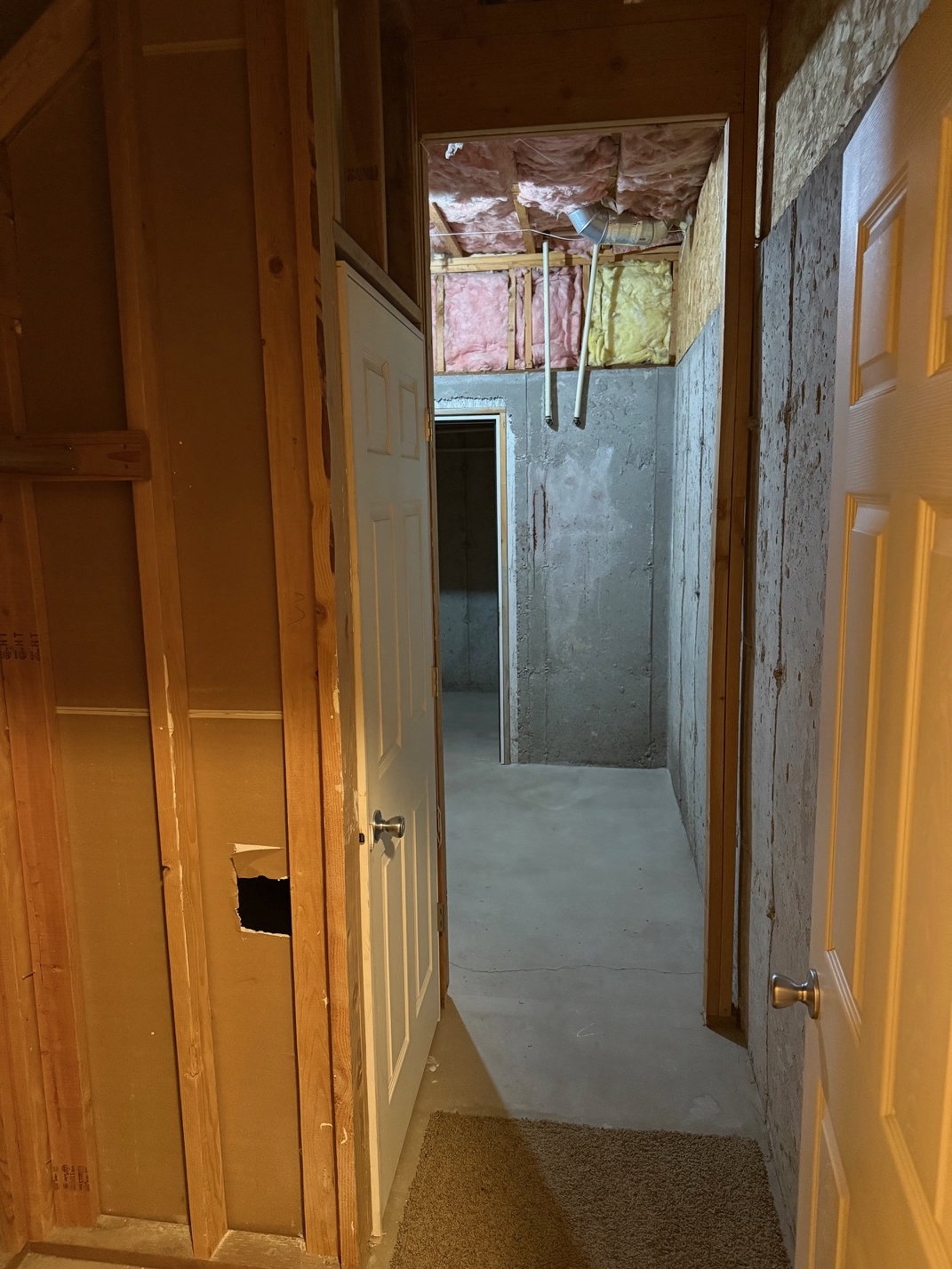 Unfinished basement area featuring exposed wood framing, concrete walls, and concrete flooring