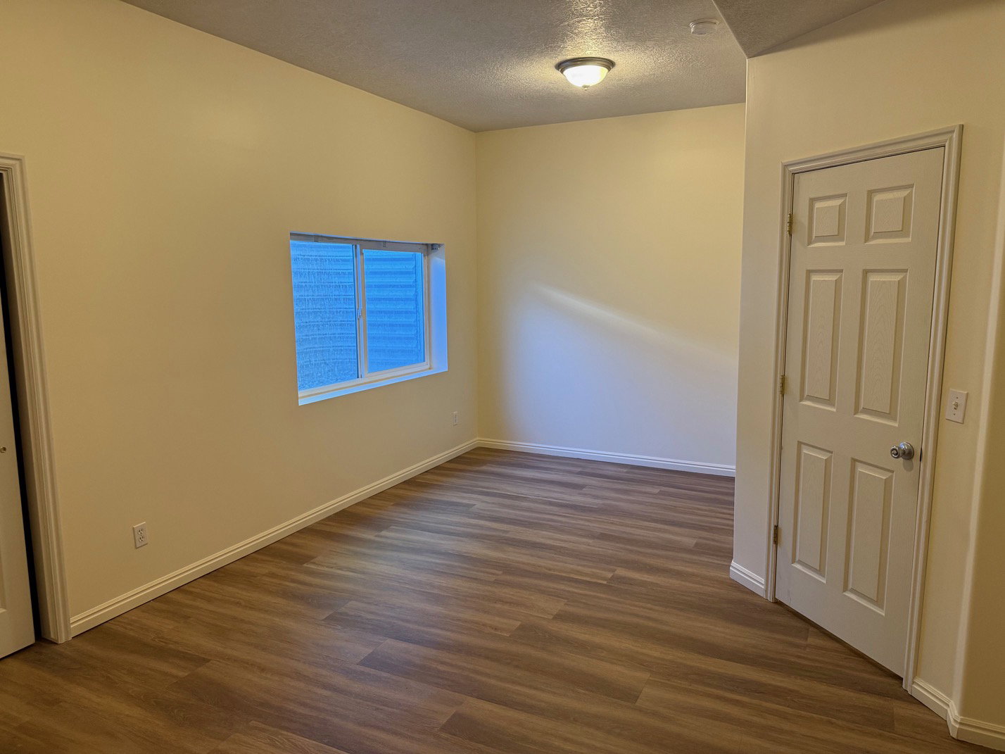 Basement bedroom featuring wood-finish flooring, neutral wall tones, and white baseboards