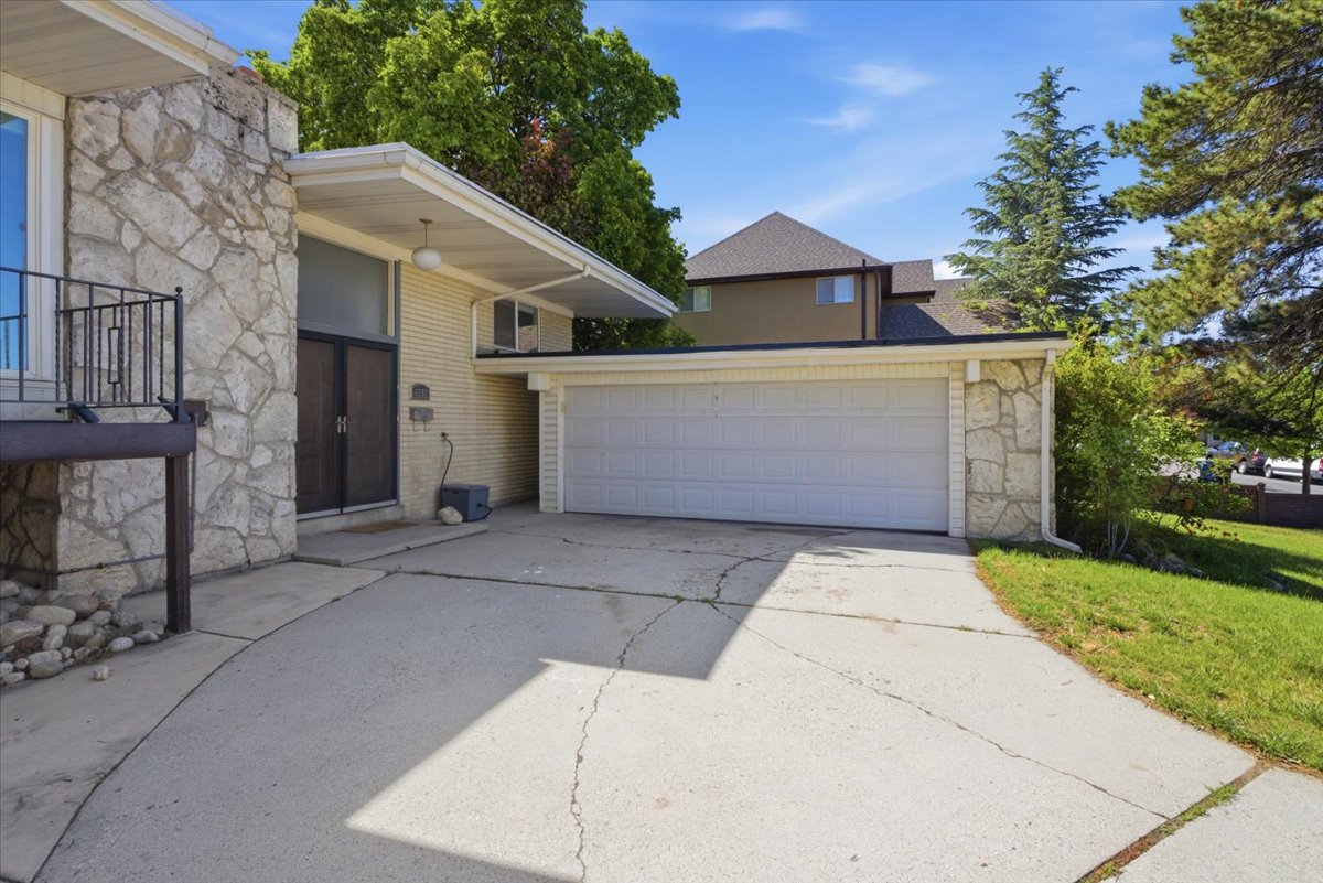 Stone veneer facade with a two-car garage, concrete driveway, and covered entry