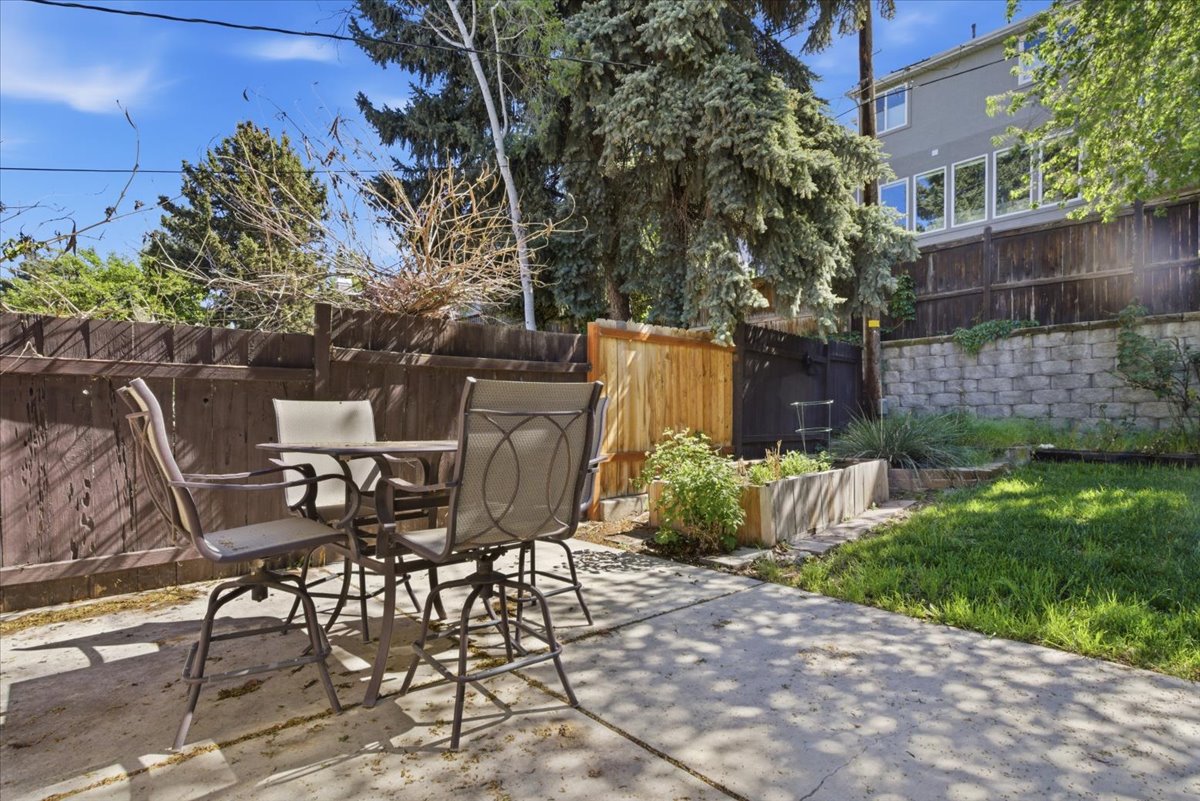 Private backyard featuring a concrete patio, wood fencing, a raised garden bed, and a landscaped retaining wall