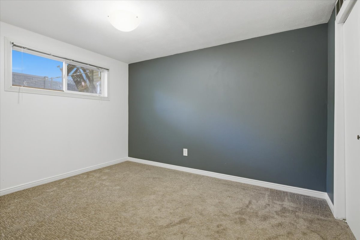 Neutral-toned carpeted room featuring a white ceiling, a white semi-flush mount light fixture, and a window with white trim
