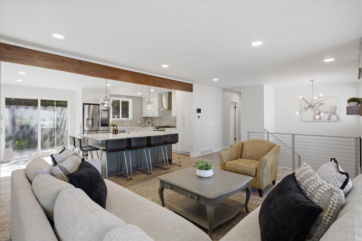 Expansive open-concept living area featuring a large kitchen island with seating, a wood-finish beam, recessed lighting, and sliding glass doors