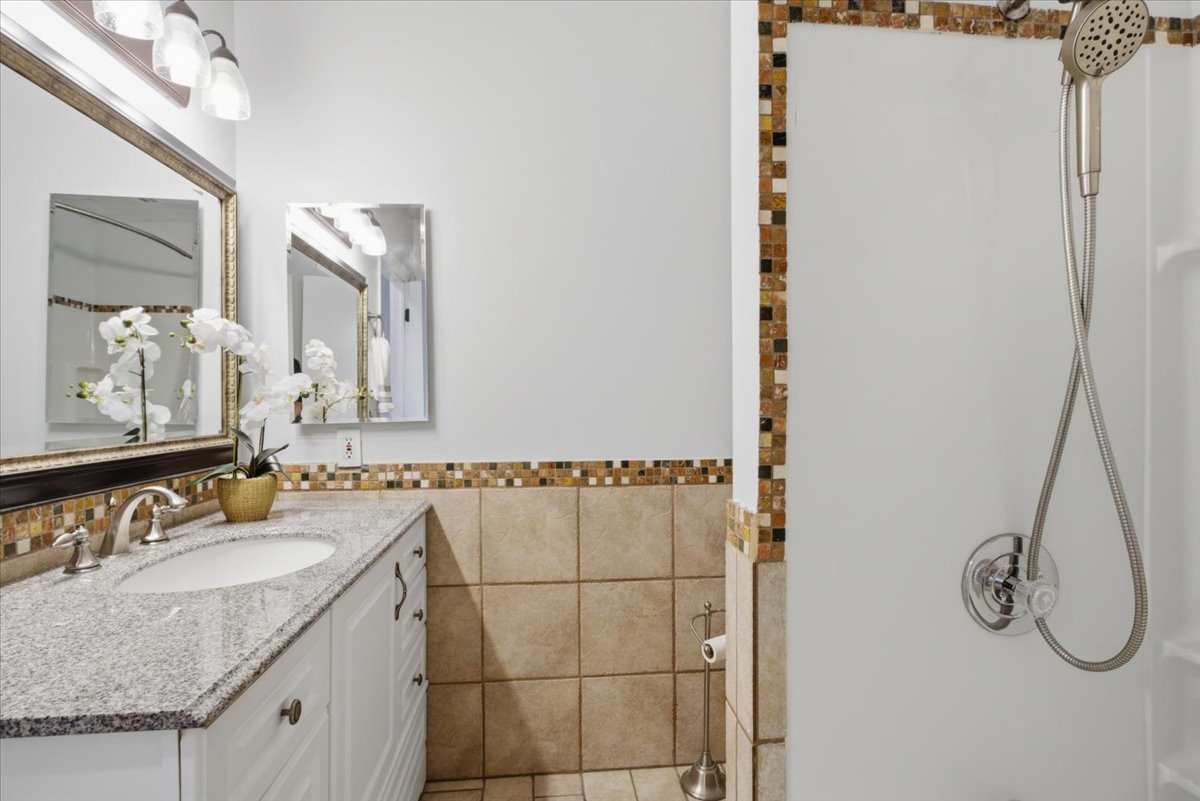 Bathroom featuring a white vanity with an undermount sink, granite countertop, and brushed nickel faucet