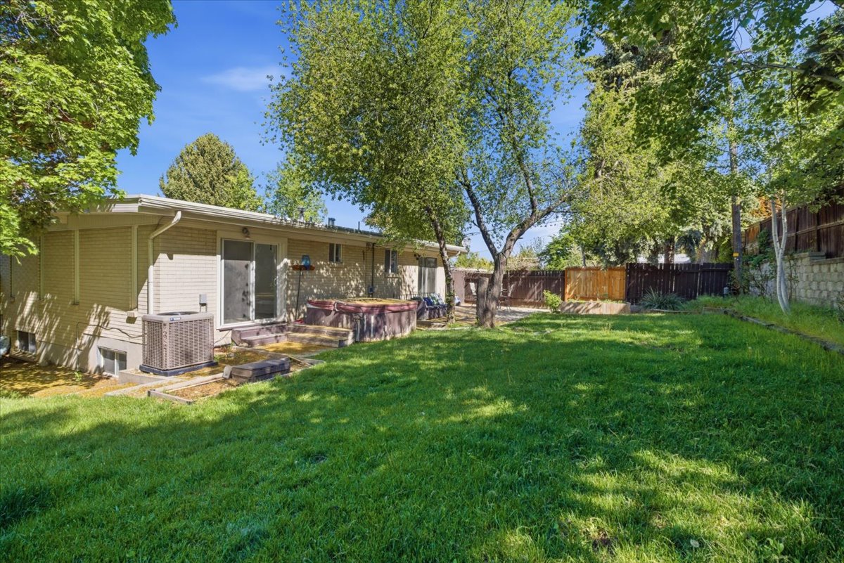 Expansive backyard featuring a manicured lawn, mature trees, and a wooden privacy fence