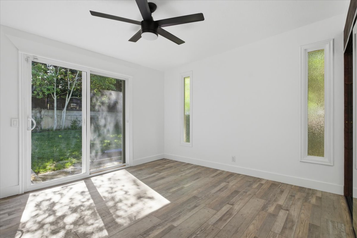 Spacious room with wood-finish flooring and a contemporary black ceiling fan