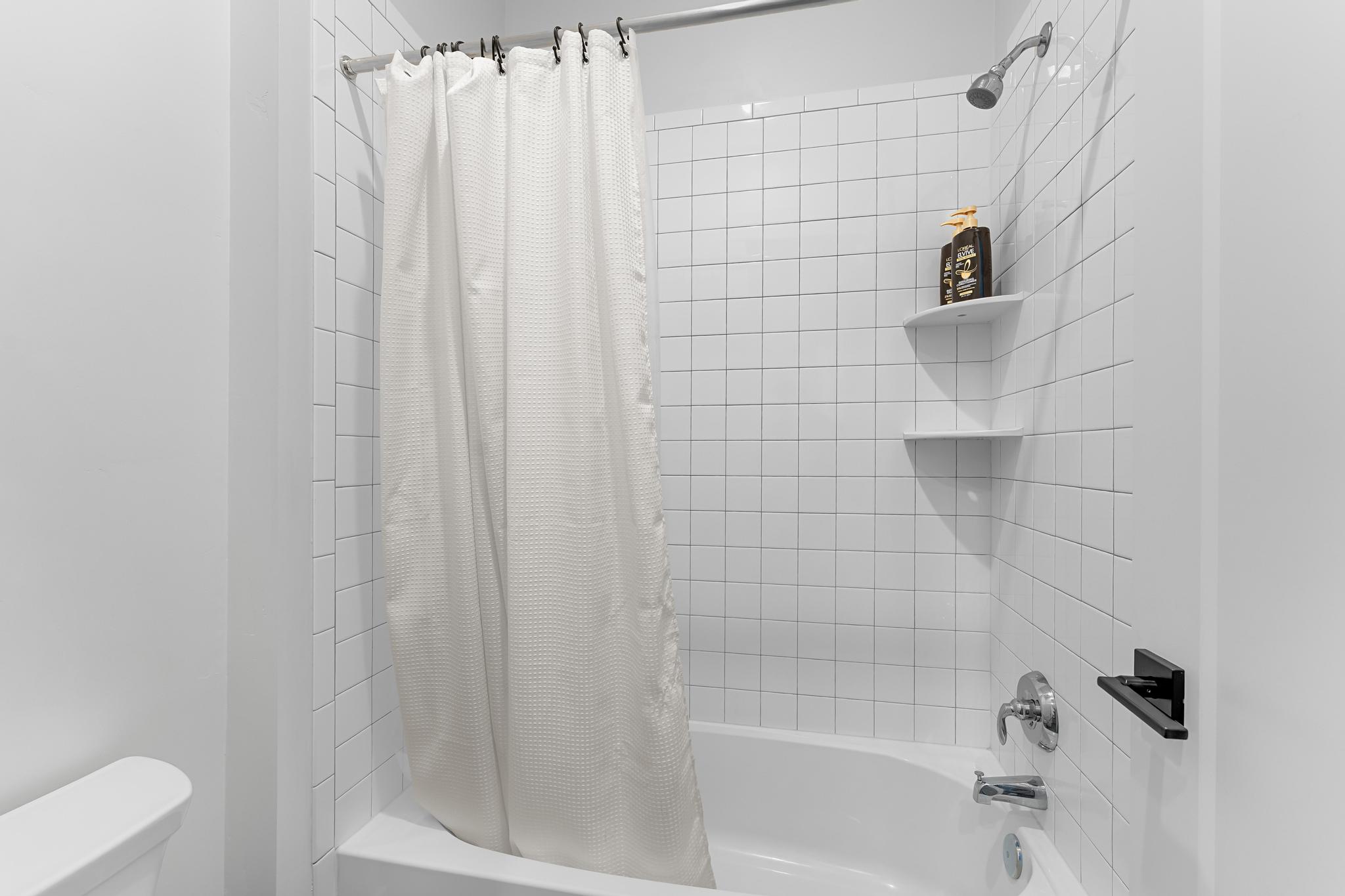 Bathtub and shower combination featuring white subway tile surround