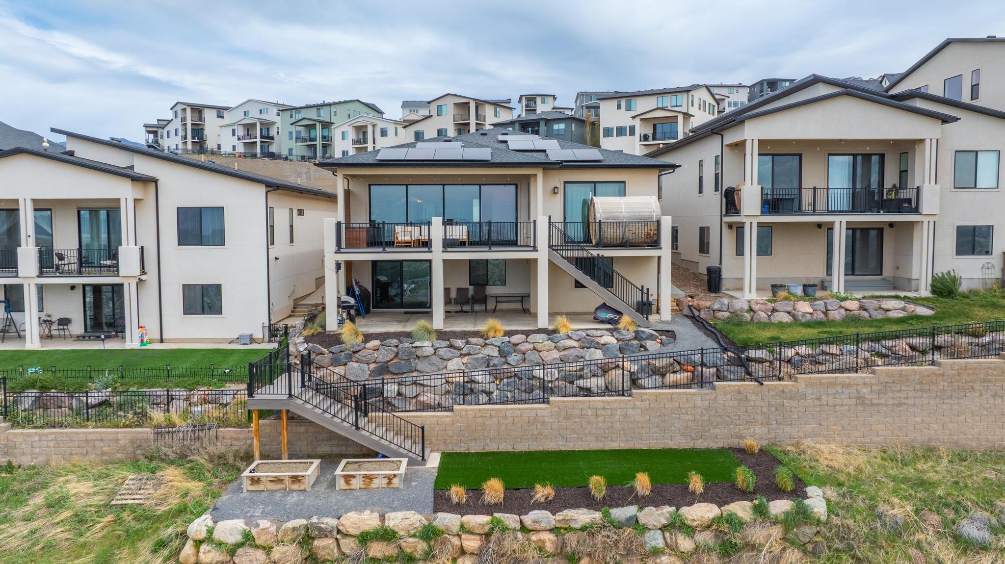 Multi-level terraced backyard featuring a rock retaining wall, artificial turf areas, and raised garden beds