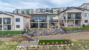 Multi-level terraced backyard featuring a rock retaining wall, artificial turf areas, and raised garden beds