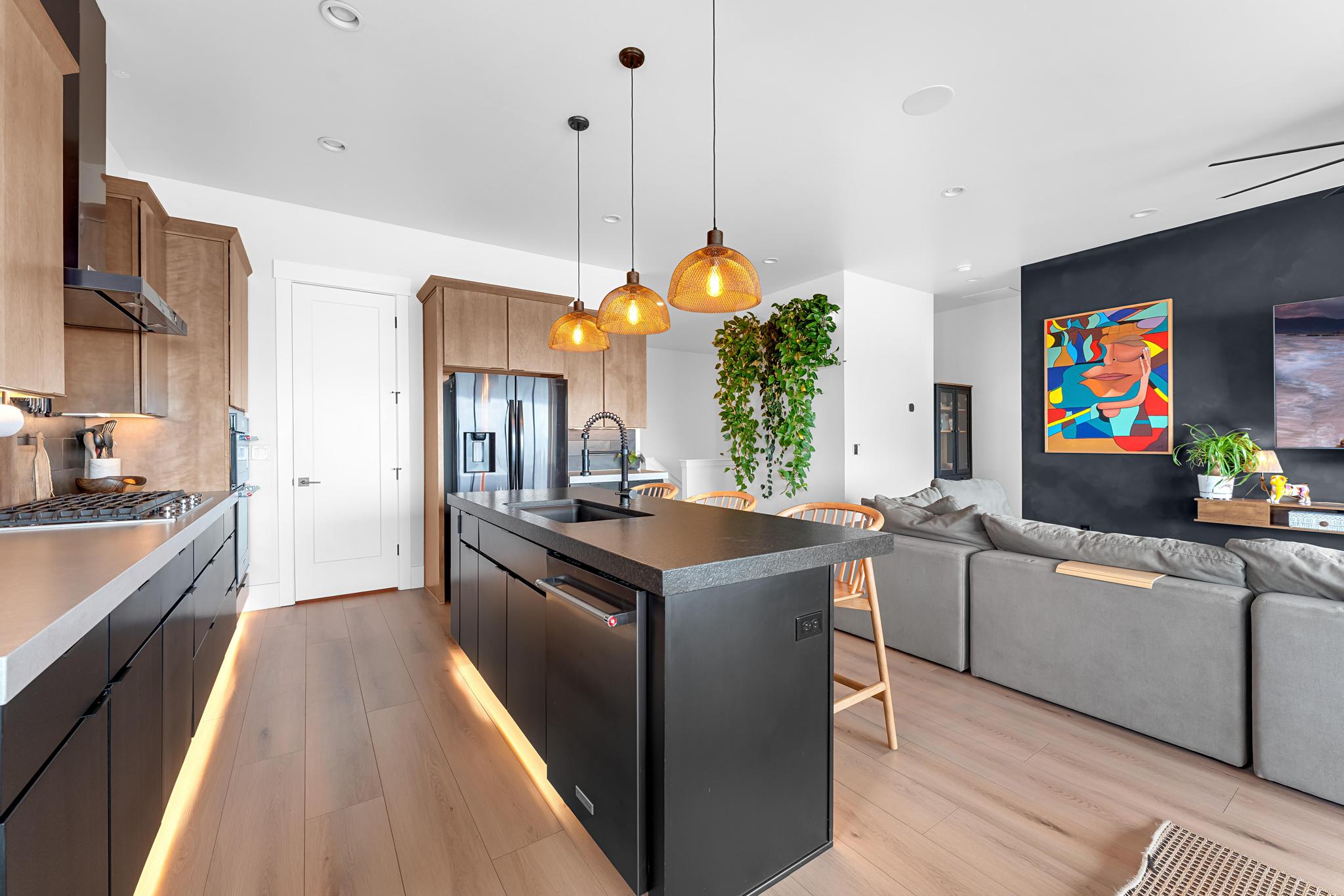 Open-concept kitchen and living area featuring wood-finish flooring, recessed lighting, and a dark accent wall