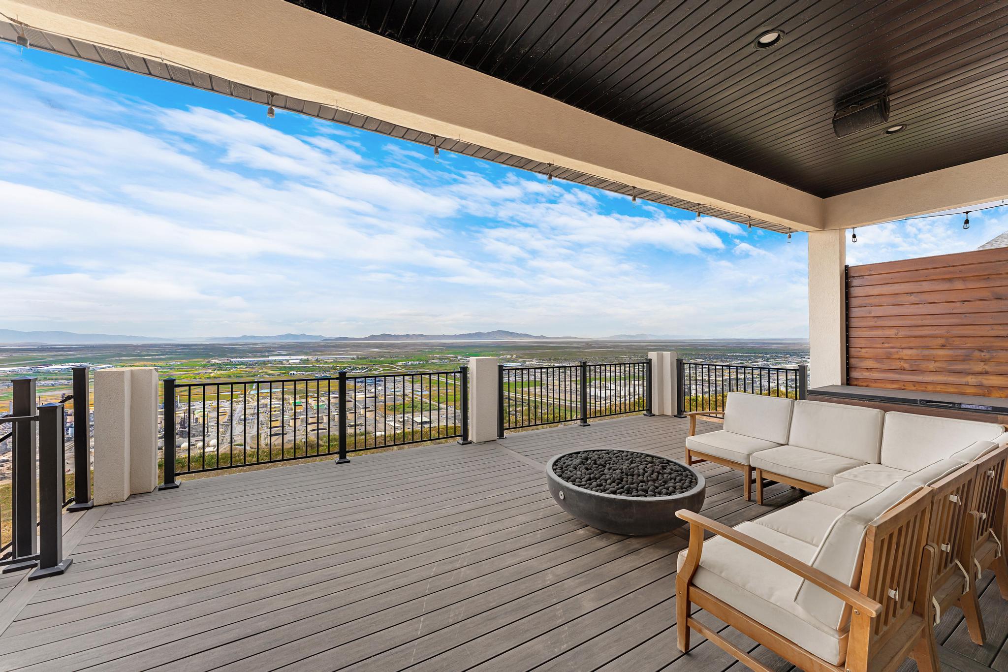 Expansive outdoor deck featuring composite decking, a metal railing, and a built-in hot tub with a wood-paneled surround