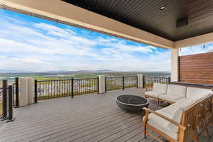 Expansive outdoor deck featuring composite decking, a metal railing, and a built-in hot tub with a wood-paneled surround
