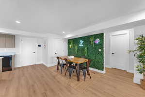 Dining area featuring a green accent wall with a wood-finish dining table and black metal chairs