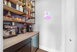 Custom beverage station featuring a built-in under-counter refrigerator, open shelving with live-edge wood, and matte black cabinetry