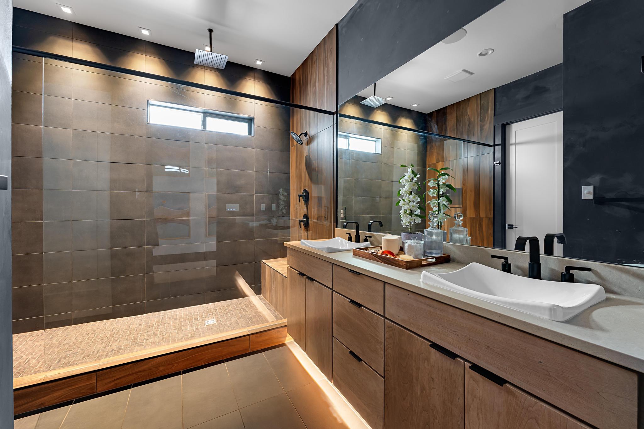 Contemporary bathroom featuring a dual vanity with undermount lighting, wood-finish cabinetry, and a large frameless mirror