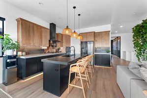 Modern kitchen featuring light wood-finish upper cabinetry, black lower cabinetry, and a substantial center island with seating for four
