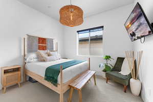Bedroom featuring light-colored carpeting and a window with a roller shade