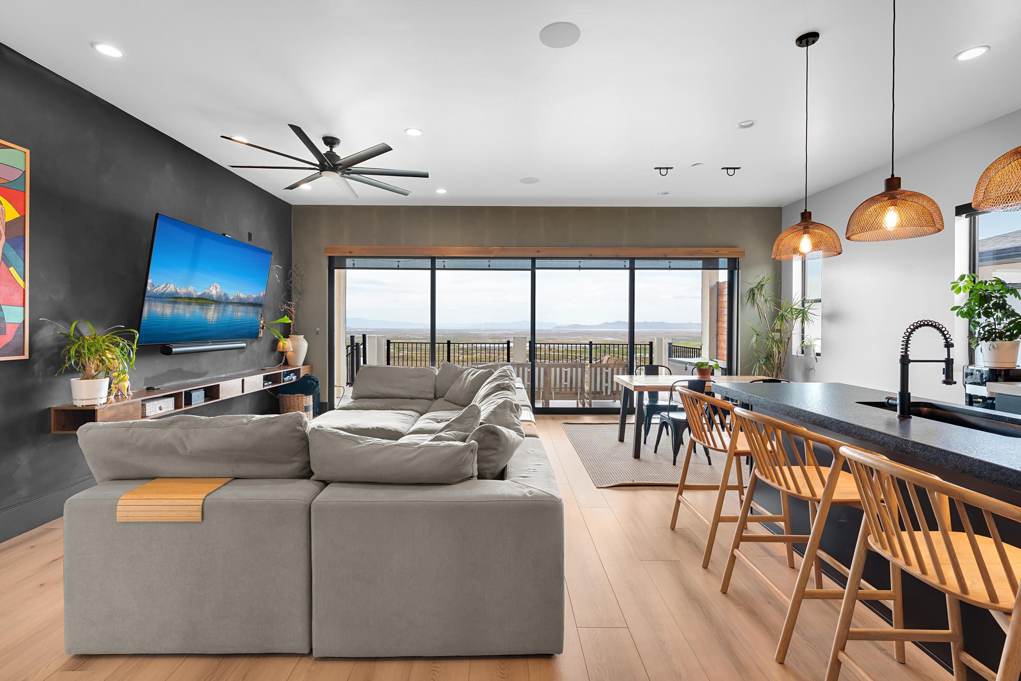 Open-concept living space featuring wood-finish flooring, a contemporary ceiling fan, and a built-in media console